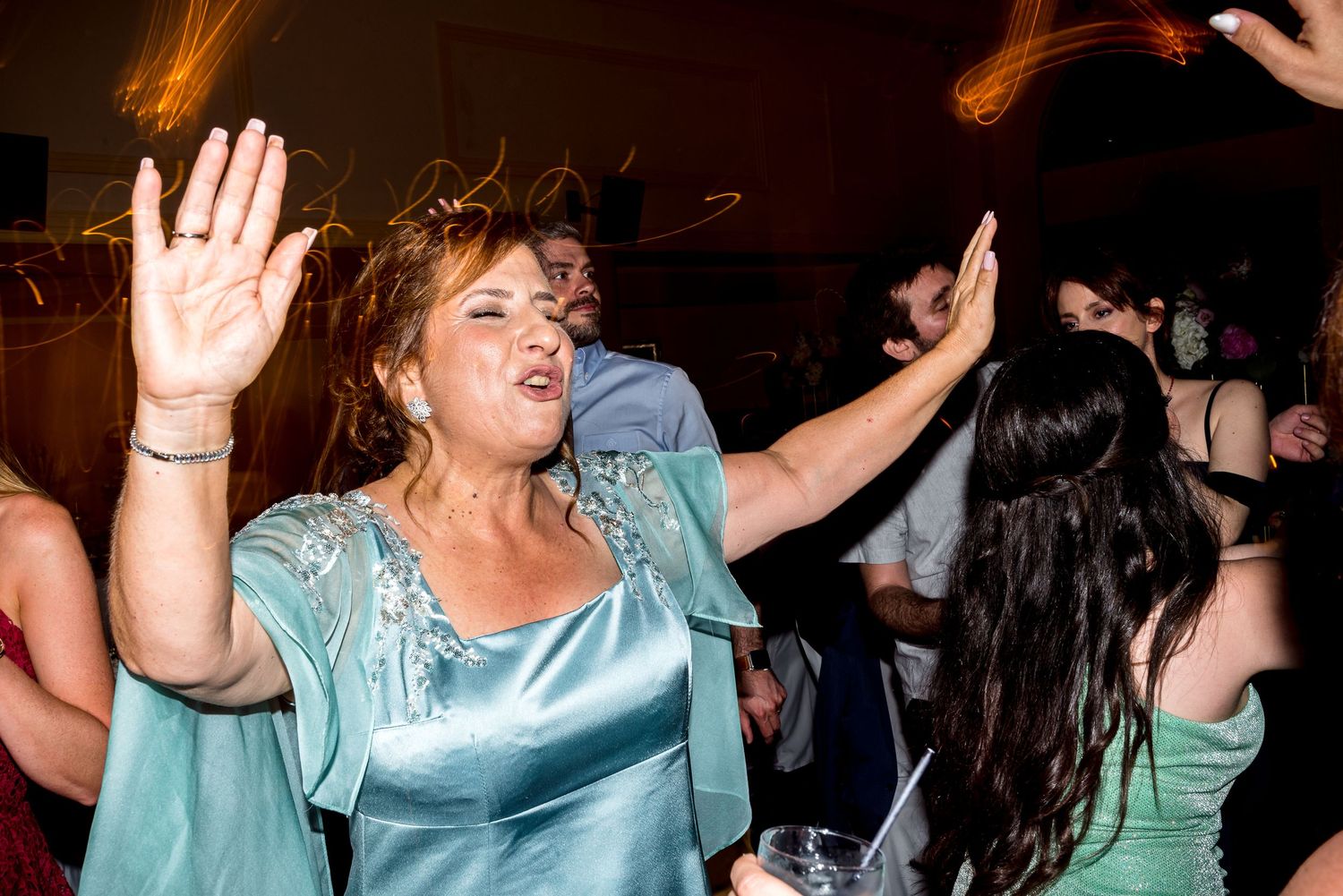Wedding guests in formal attire dancing and celebrating at an evening reception.