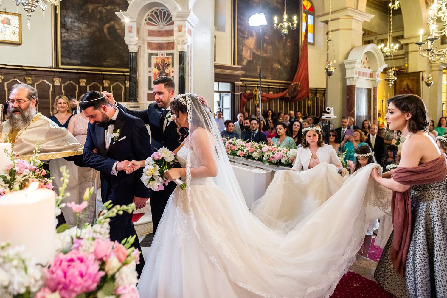 Traditional church wedding ceremony with ornate decorations and pink floral arrangements.