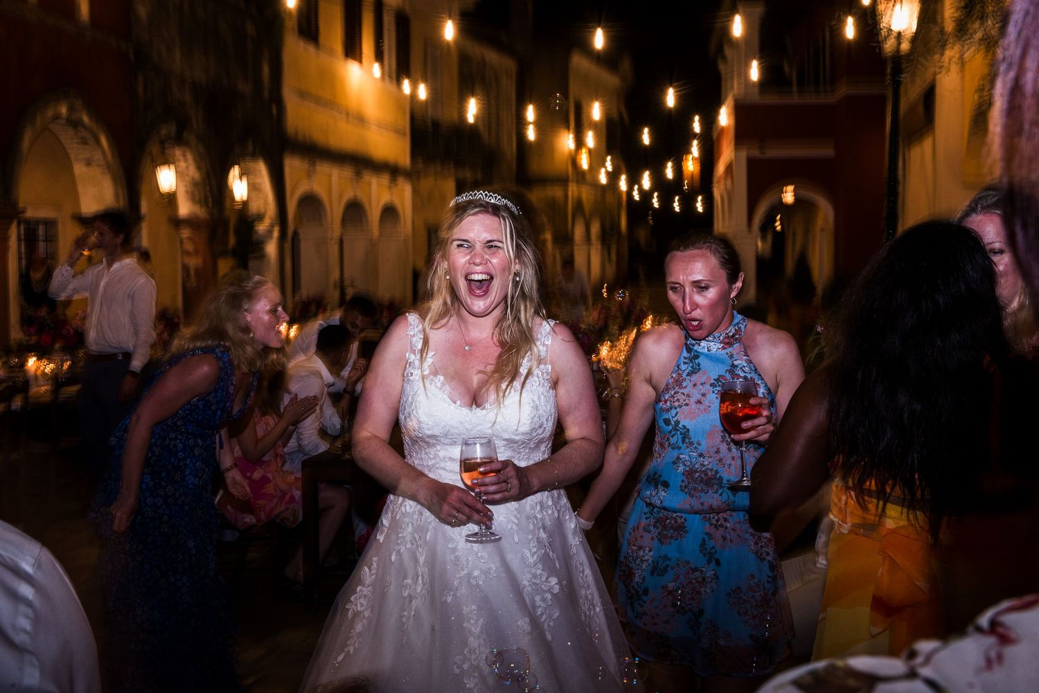 Wedding reception dance party with colorful lighting and guests dancing on a crowded dance floor.