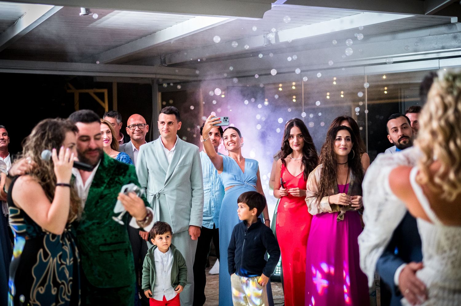 Wedding reception dance floor filled with celebrating guests and colorful lights.