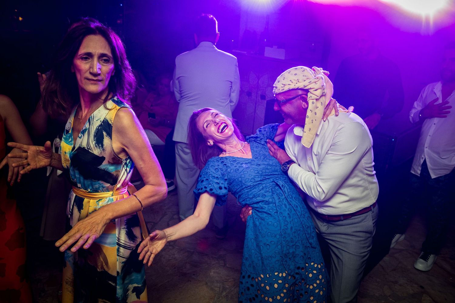 Dance floor bathed in purple lighting as guests celebrate at nighttime event.