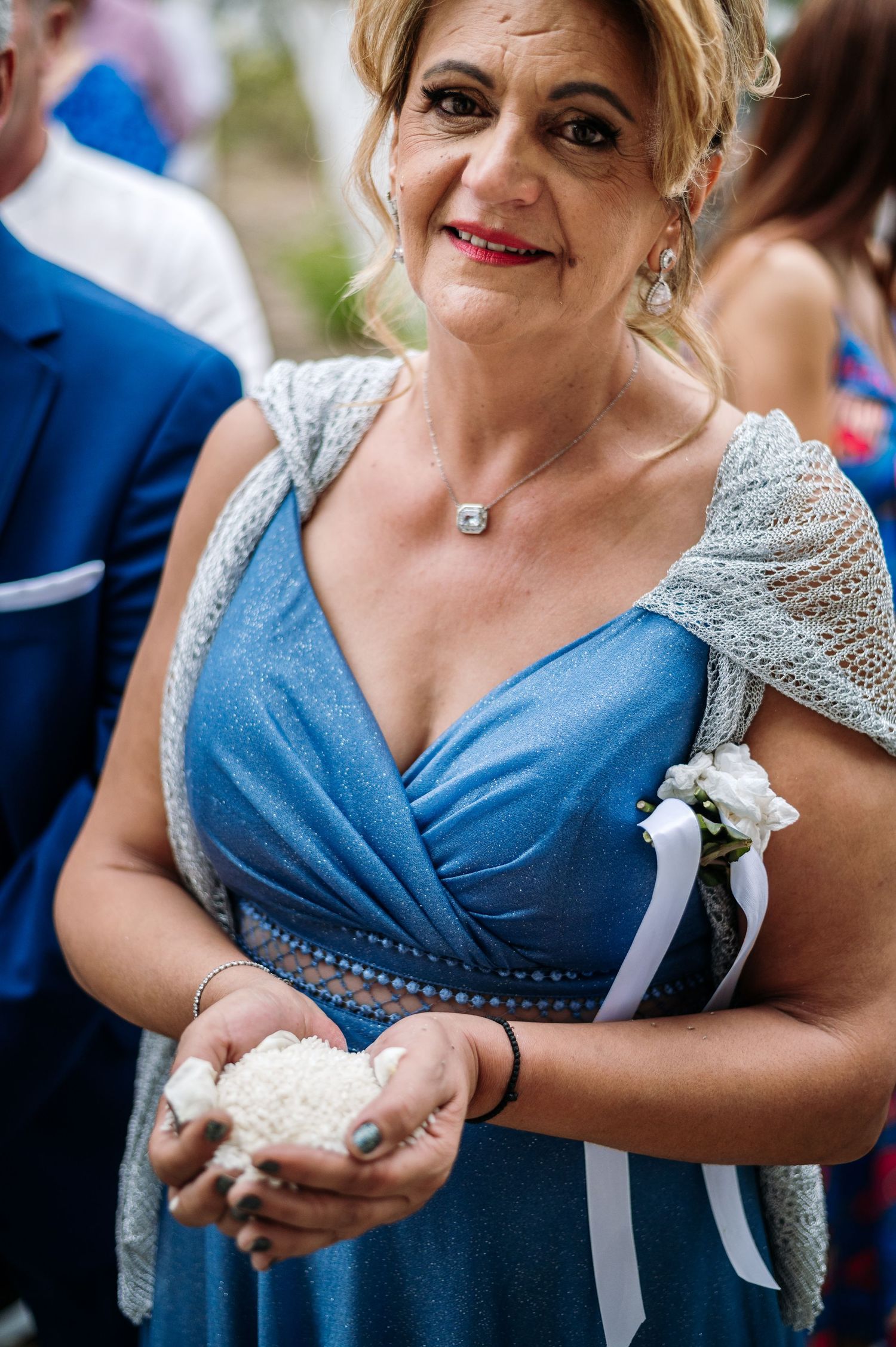 Wedding guest in a blue dress holds a white dove before a ceremonial release.