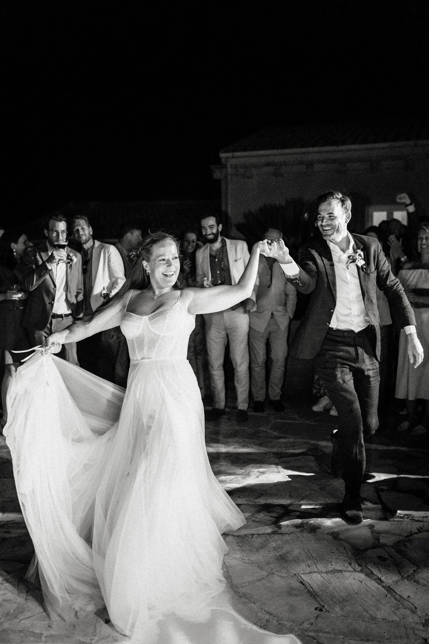 Black and white photo of brides twirling in white dresses on the dance floor.