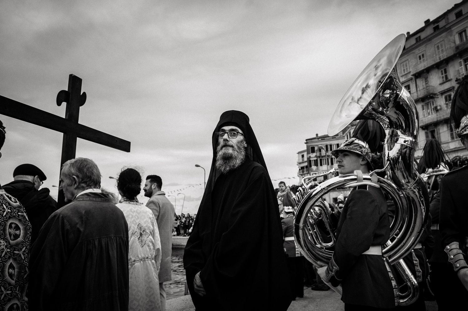 Orthodox religious procession with clergy and faithful gathered outdoors in black and white.