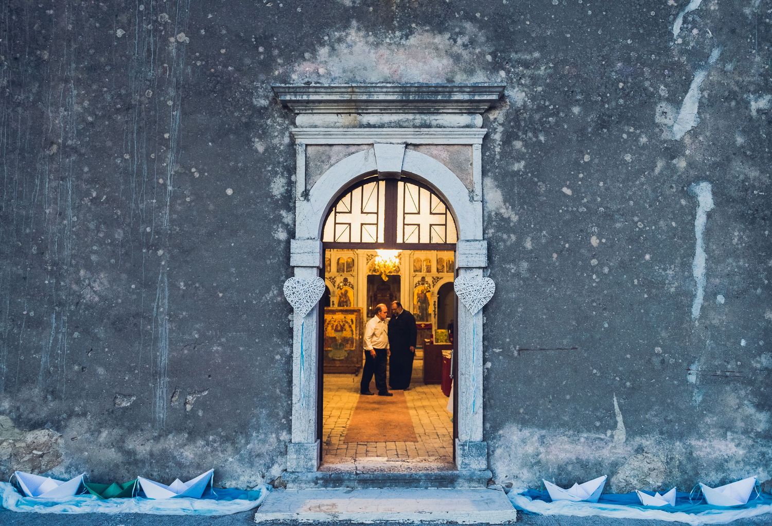 A stone archway frames people gathered inside a church for a ceremony.