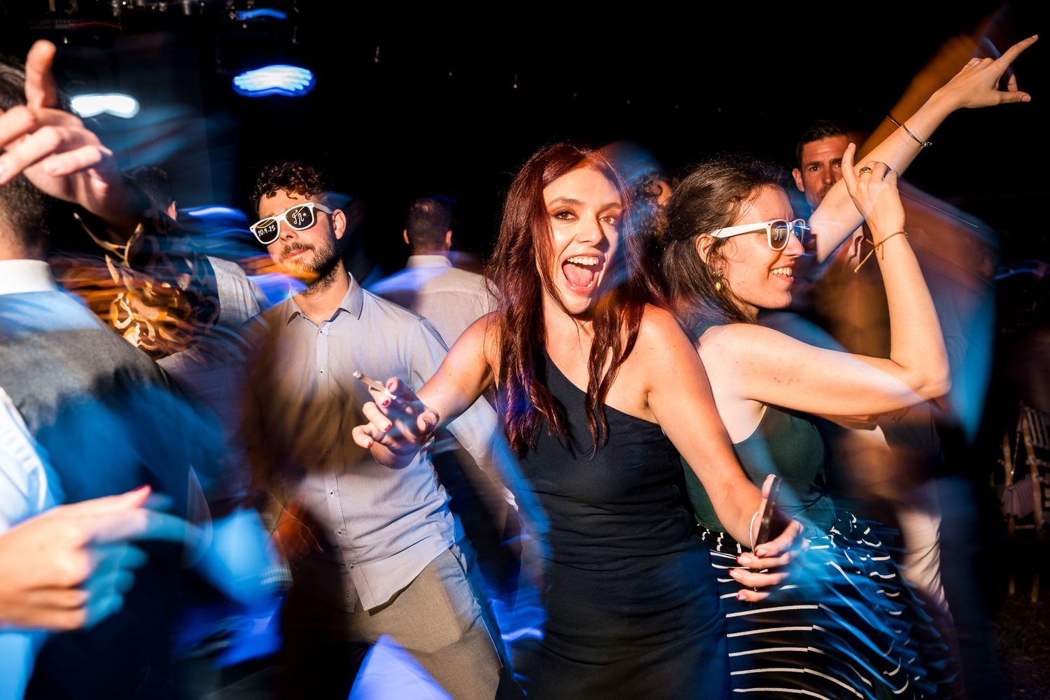 Dynamic party scene with dancers moving in motion blur under blue lighting.
