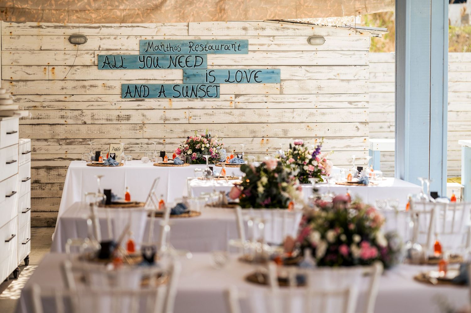 Wedding reception setup with rustic white decor and floral centerpieces.