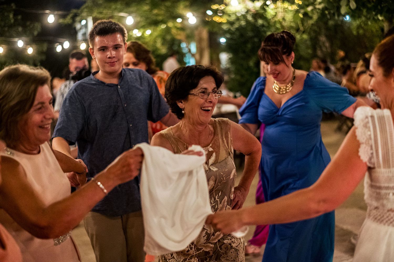 Wedding guests dance and socialize during an outdoor evening celebration.