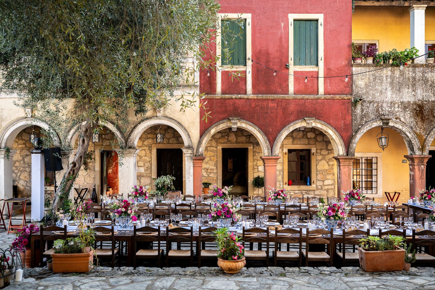 Mediterranean restaurant terrace with red walls and arched columns overlooking an outdoor dining area.