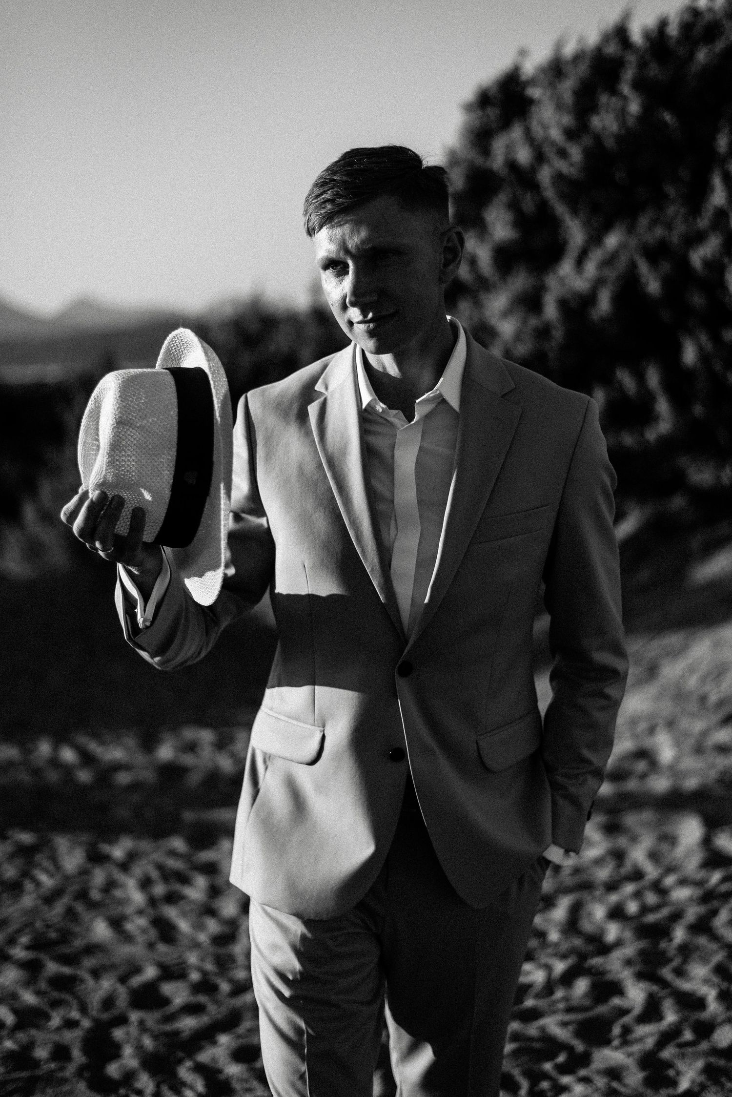 Artistic black and white wedding photography captures intimate moments on a sandy hillside.