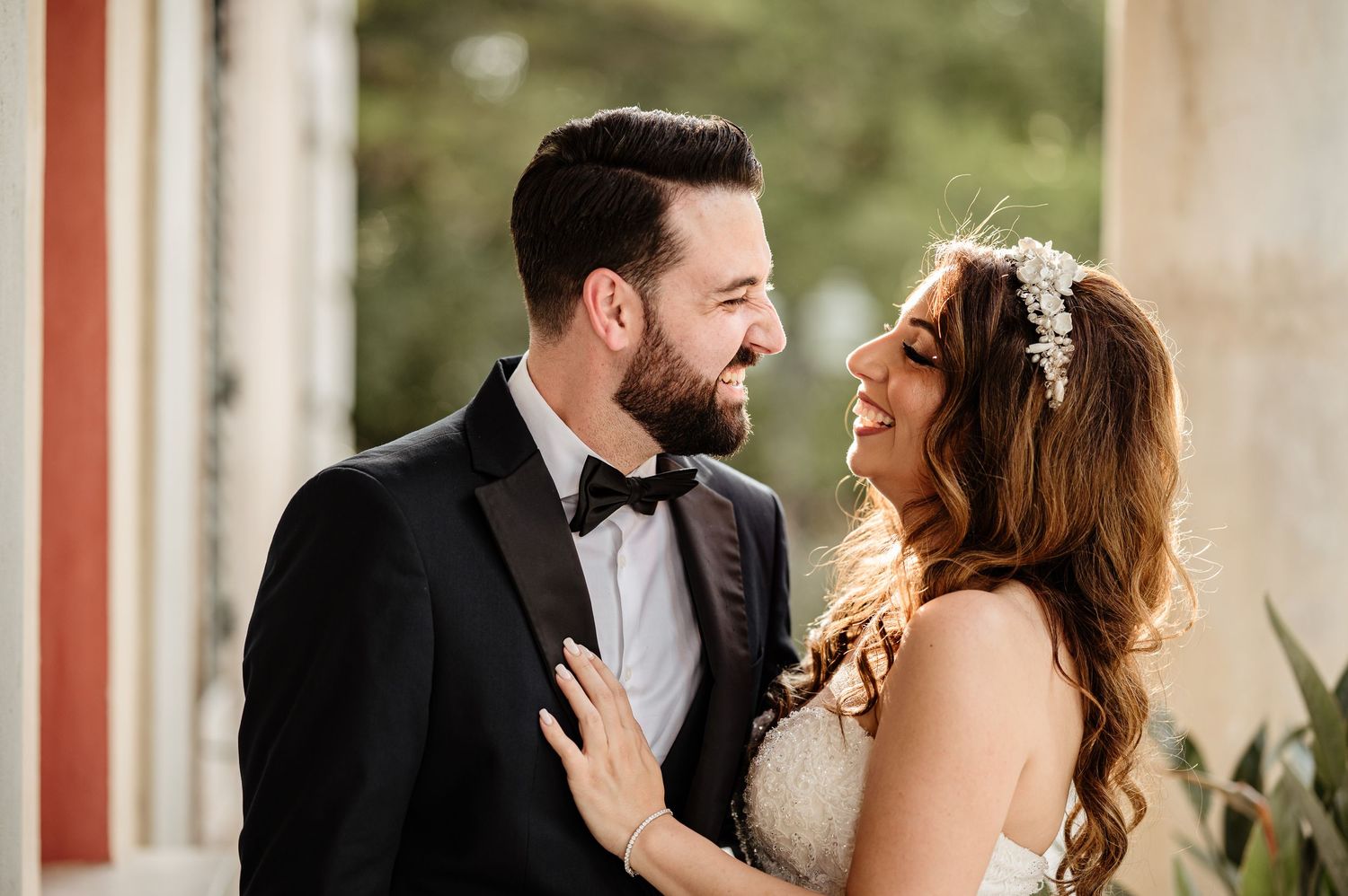 A romantic wedding couple shares intimate moments in an elegant columned courtyard setting.