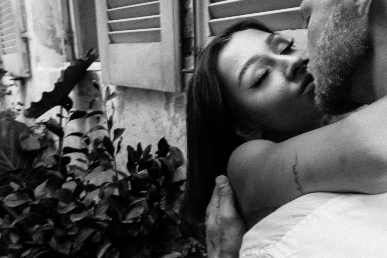 Intimate black and white portrait with greenery and soft natural lighting.