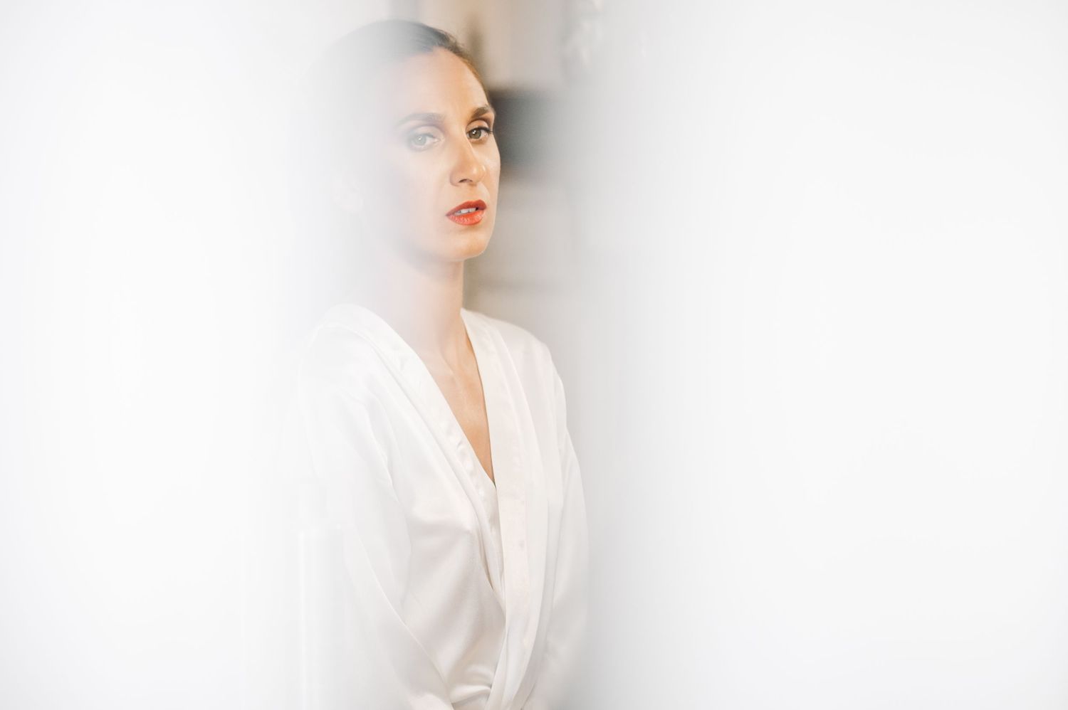 Minimalist high-key portrait against white background wearing white clothing.