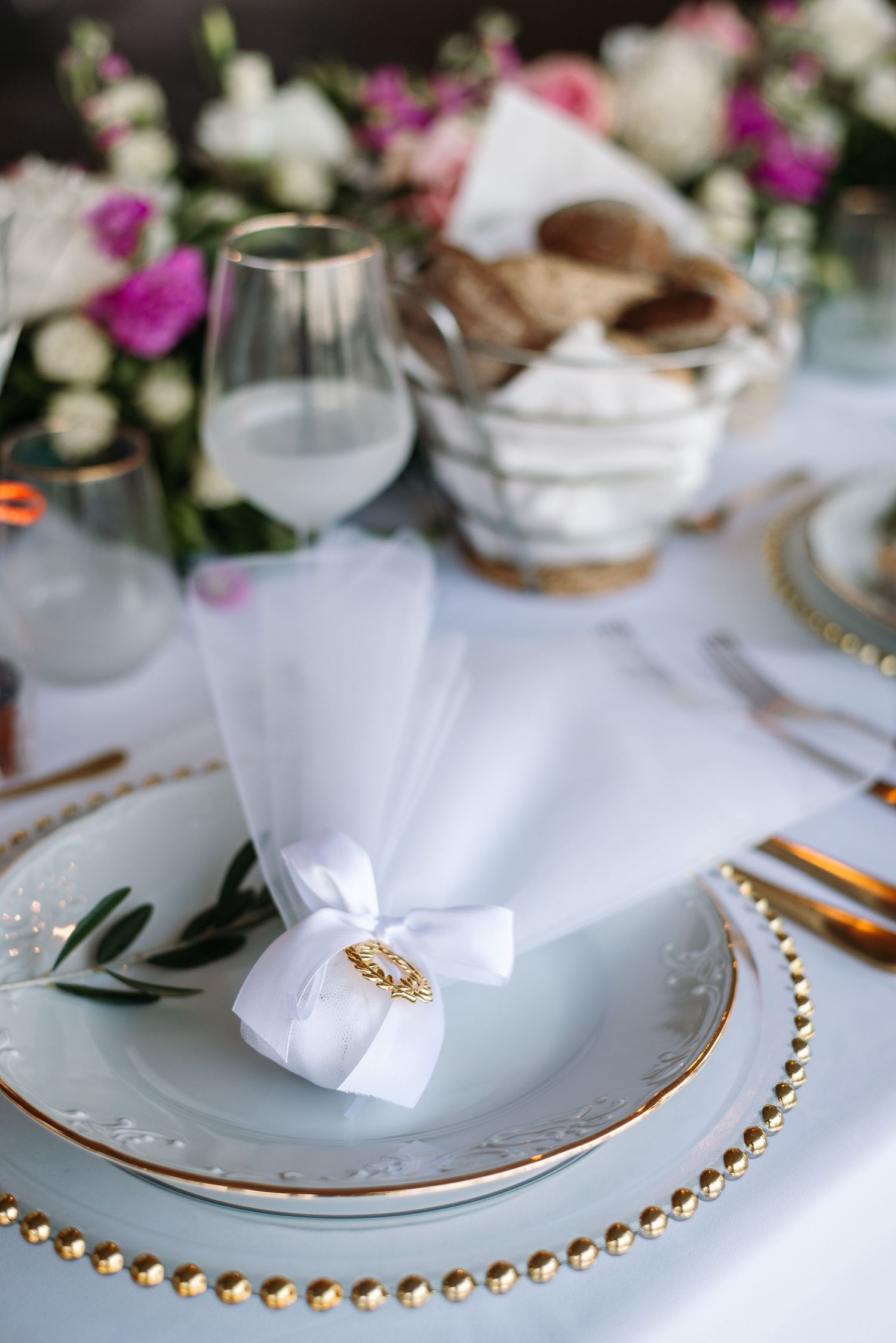 Elegant table setting with gold-rimmed plates and white napkins for a wedding reception.