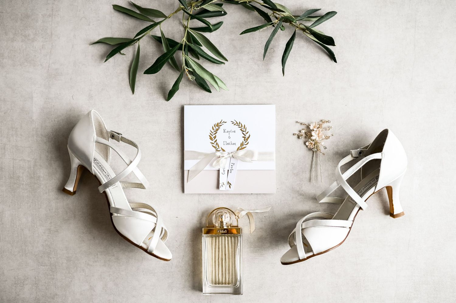 Wedding day details including olive branches, perfume bottle, and white bridal shoes.