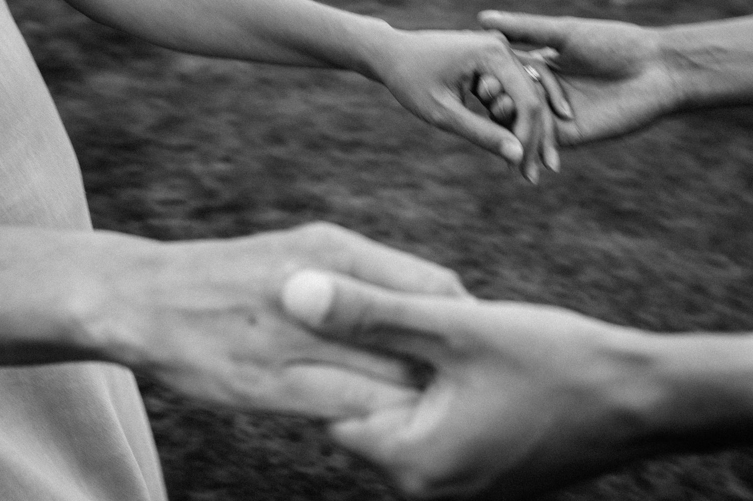 Artistic black and white close-up of hands reaching for each other.
