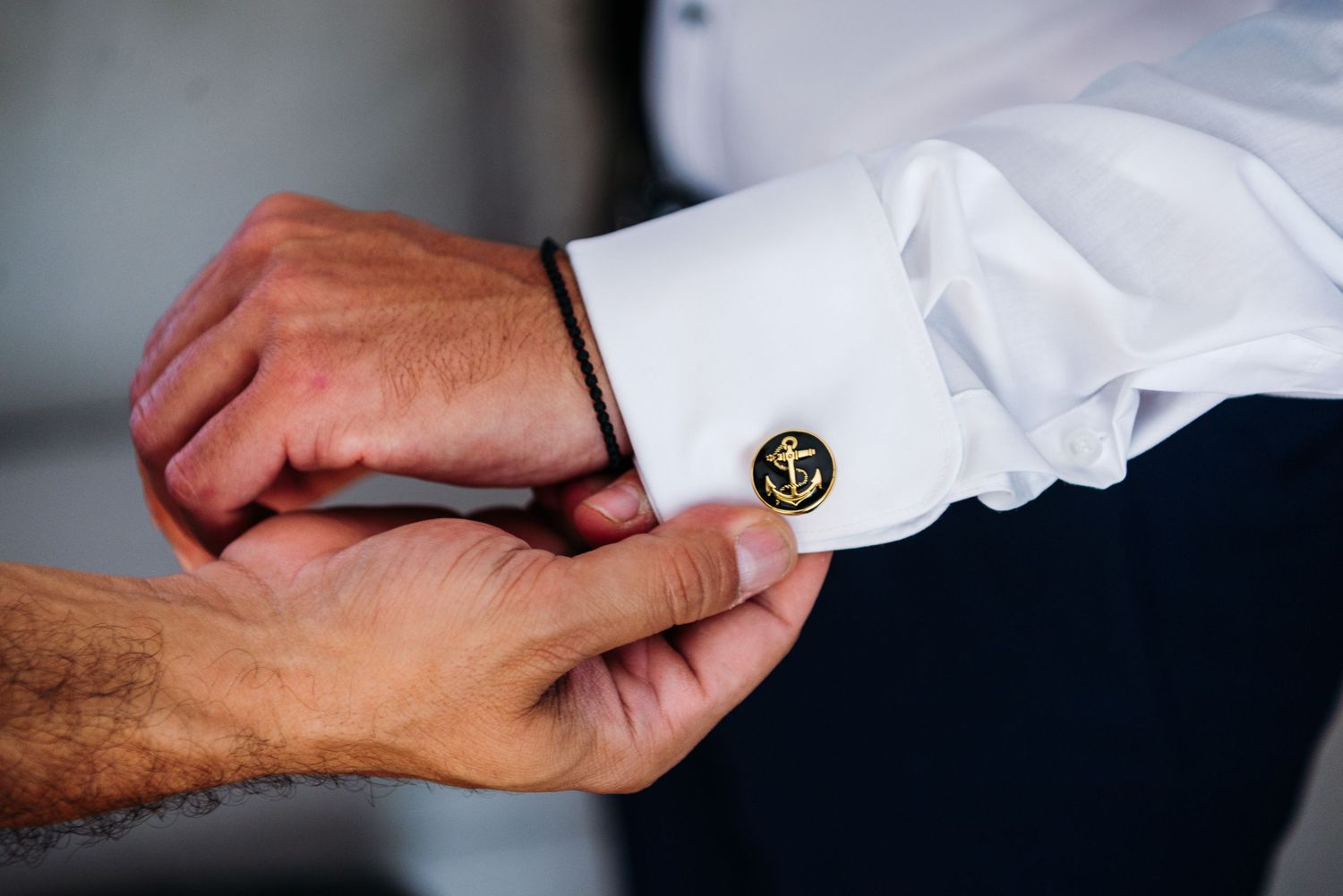 Close-up shot of hands adjusting a white dress shirt cuff and sleeve.
