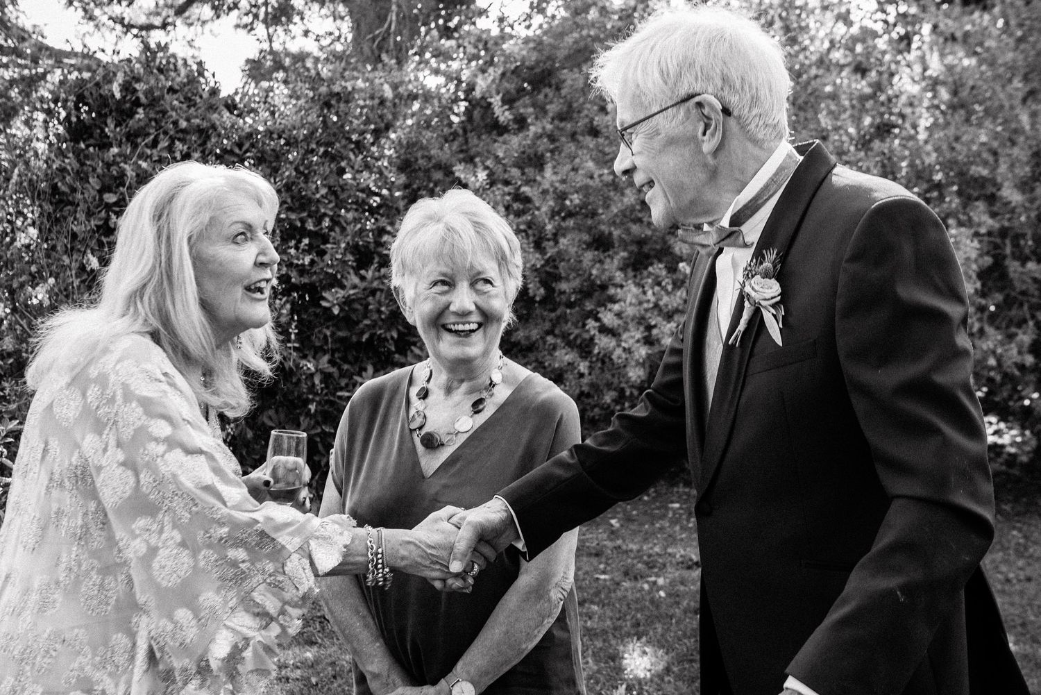 Black and white candid moments shared between wedding guests during outdoor celebrations.