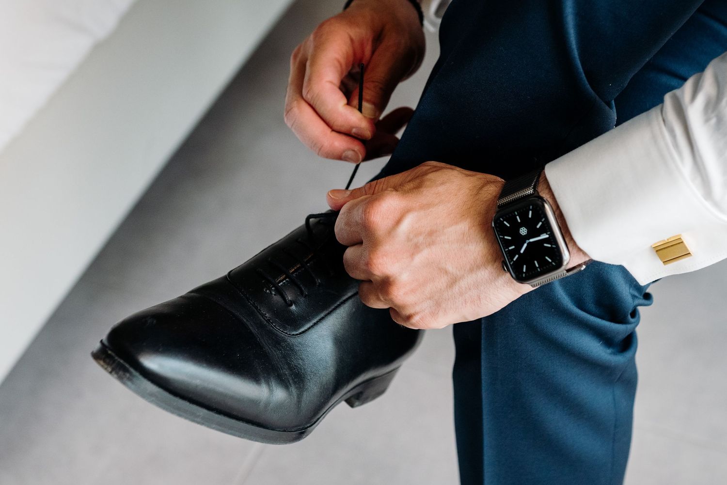 Close-up shots of hands adjusting formal black dress shoes and clothing details.