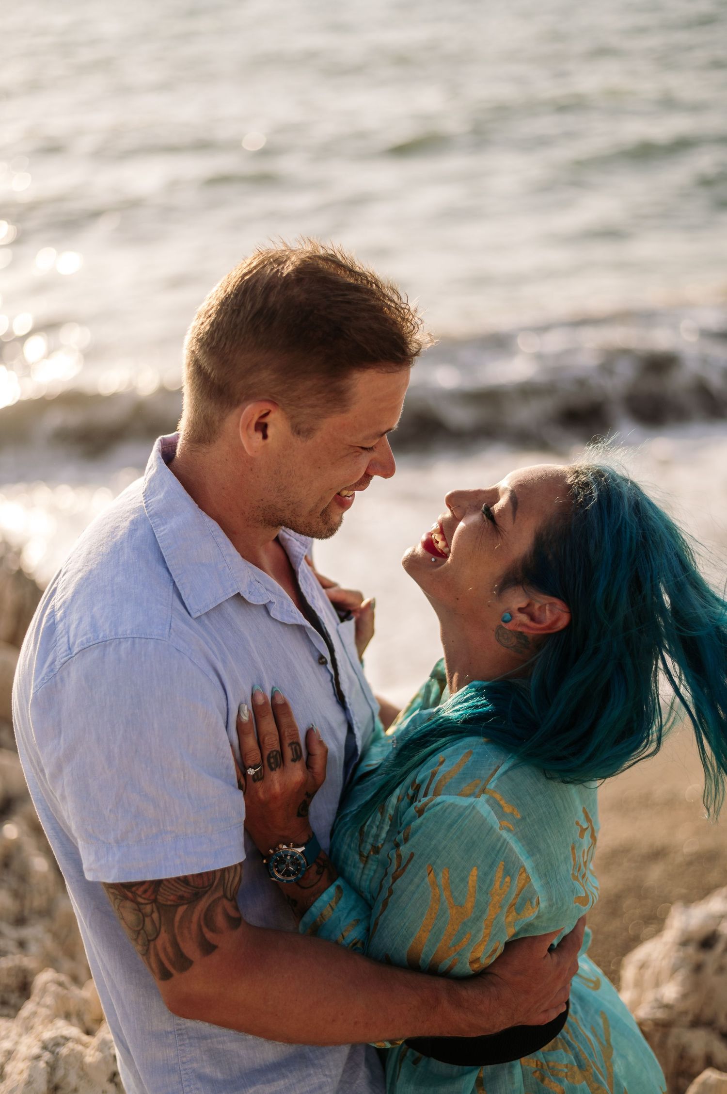 A romantic couple embraces by the ocean during sunset, creating a tender moment.