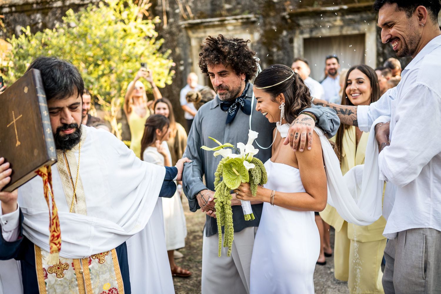 Guests celebrate at an outdoor wedding with natural lighting and casual atmosphere.