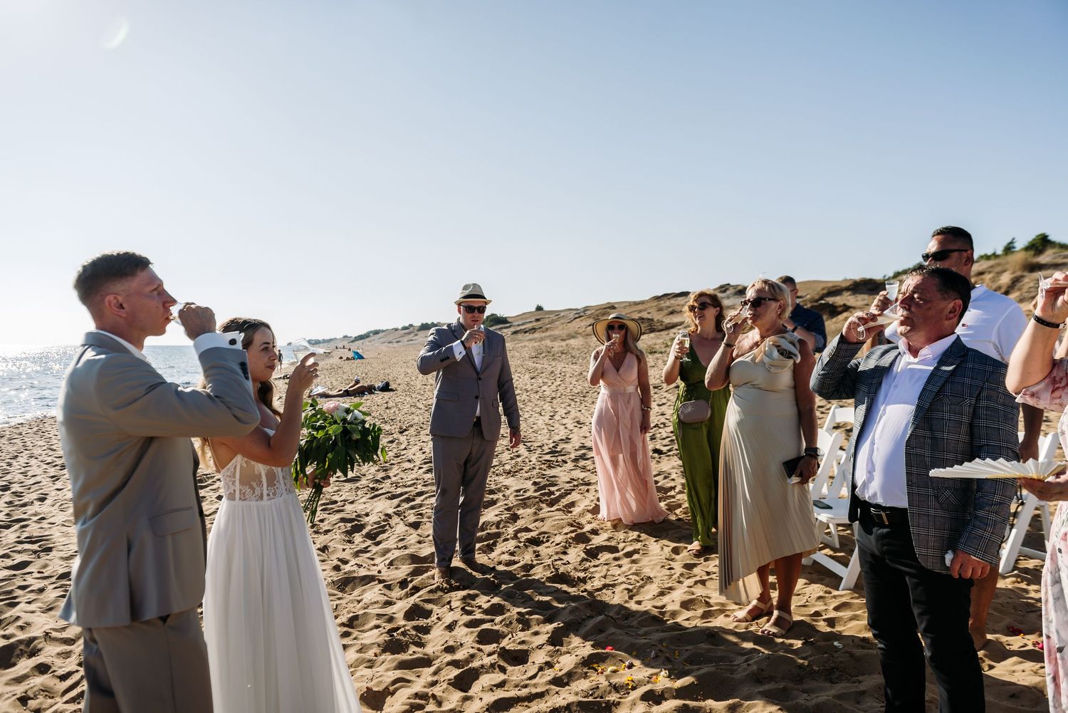 Wedding guests gather on sandy beach to witness ceremony.