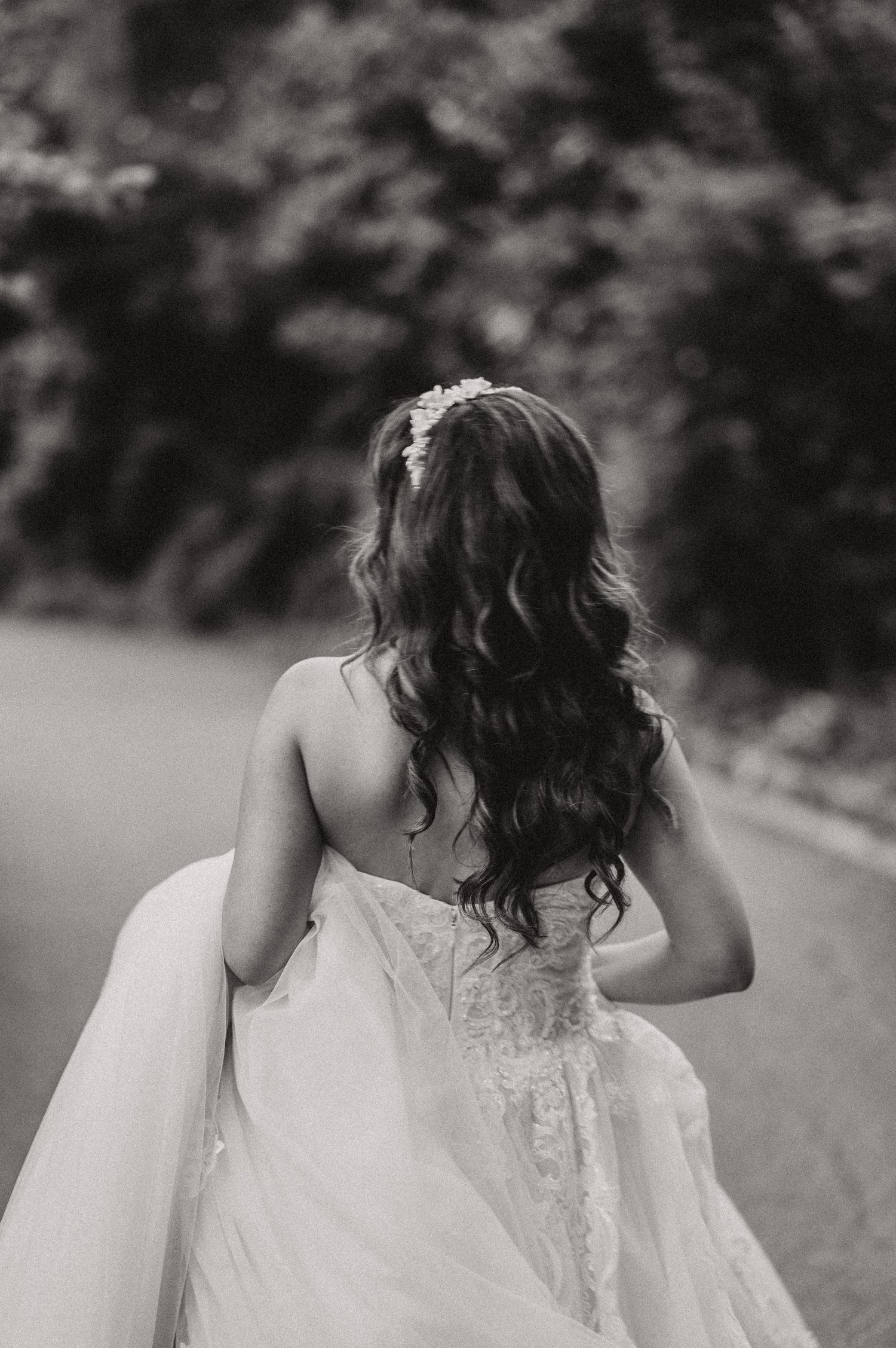 Close-up details of a bride's lace wedding dress and flowing veil in black and white.
