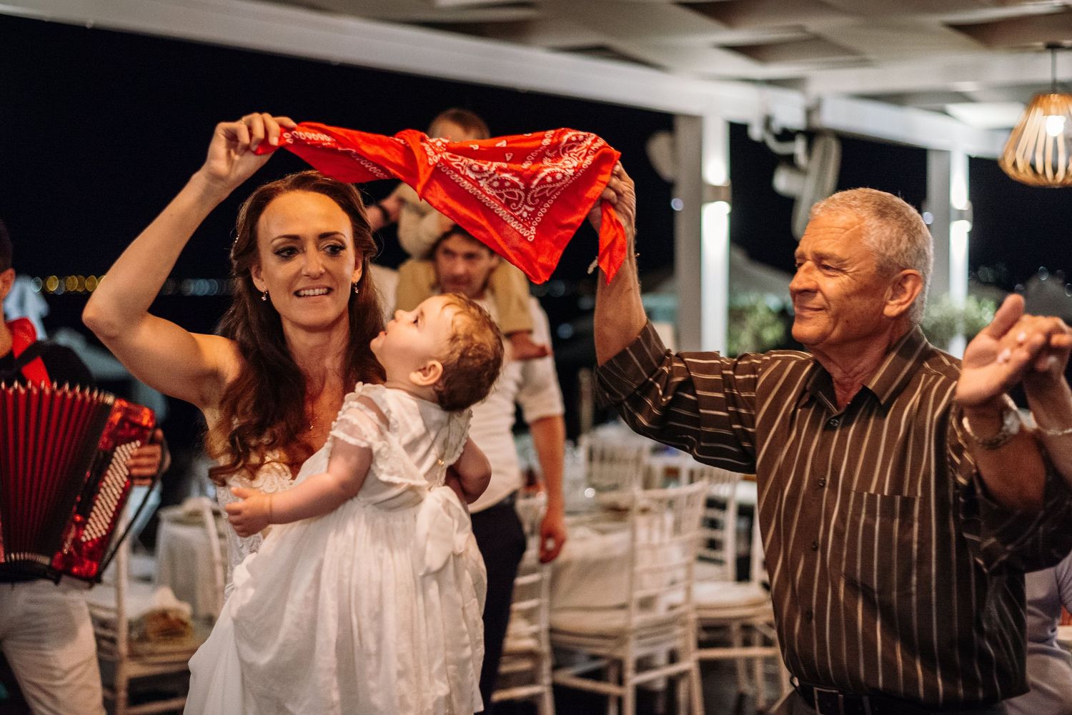 Wedding guests dancing and waving red napkins during reception celebrations.