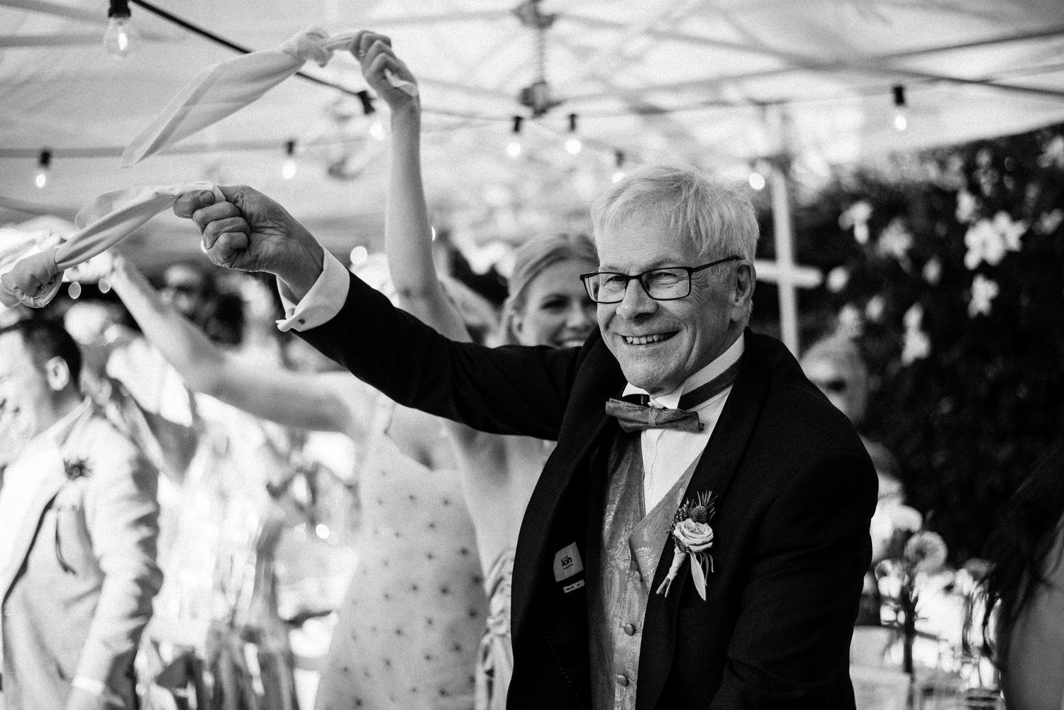 Joyful celebration under white canopy tent with guests raising arms in excitement.