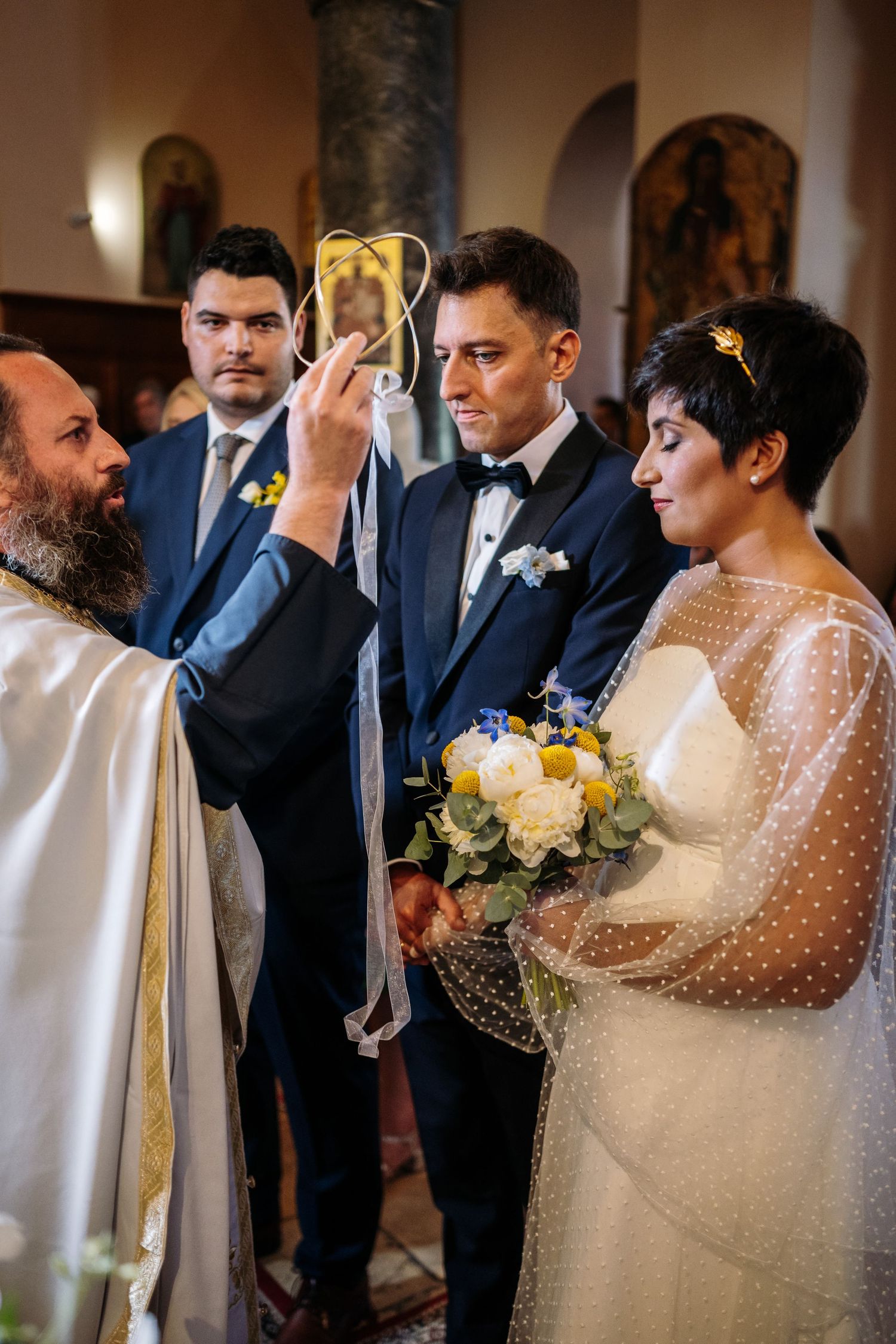 Wedding ceremony in elegant church interior with white and yellow flower decorations.