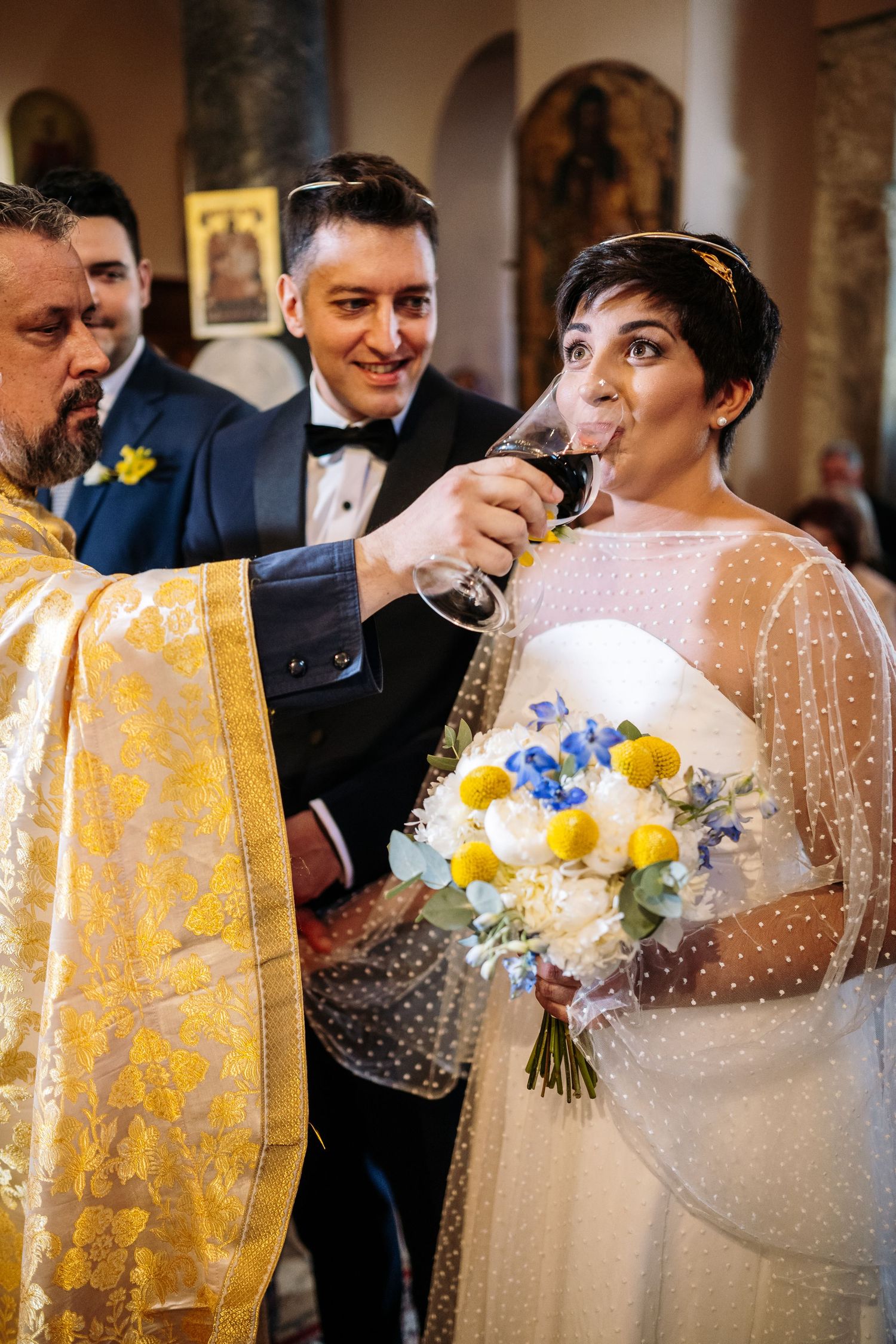 Close-up of bridal bouquet with blue and yellow flowers against lace dress details.