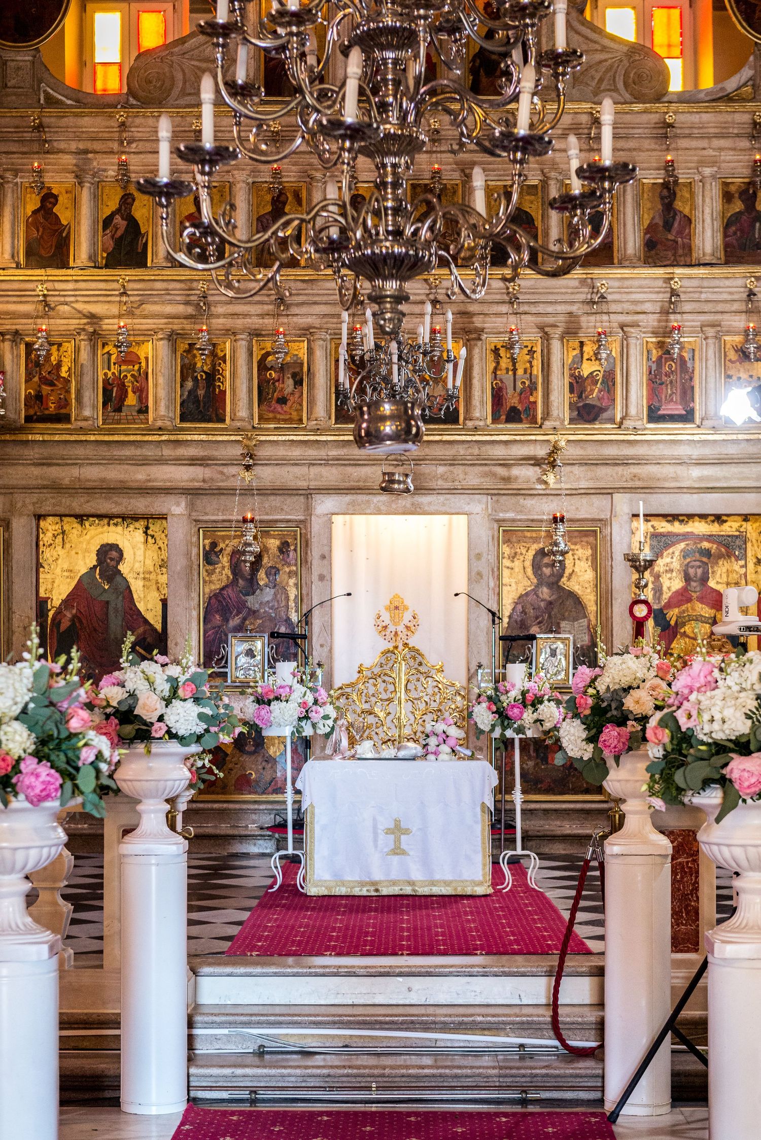 Ornate church interior decorated with white pillars and pink floral arrangements for a wedding ceremony.