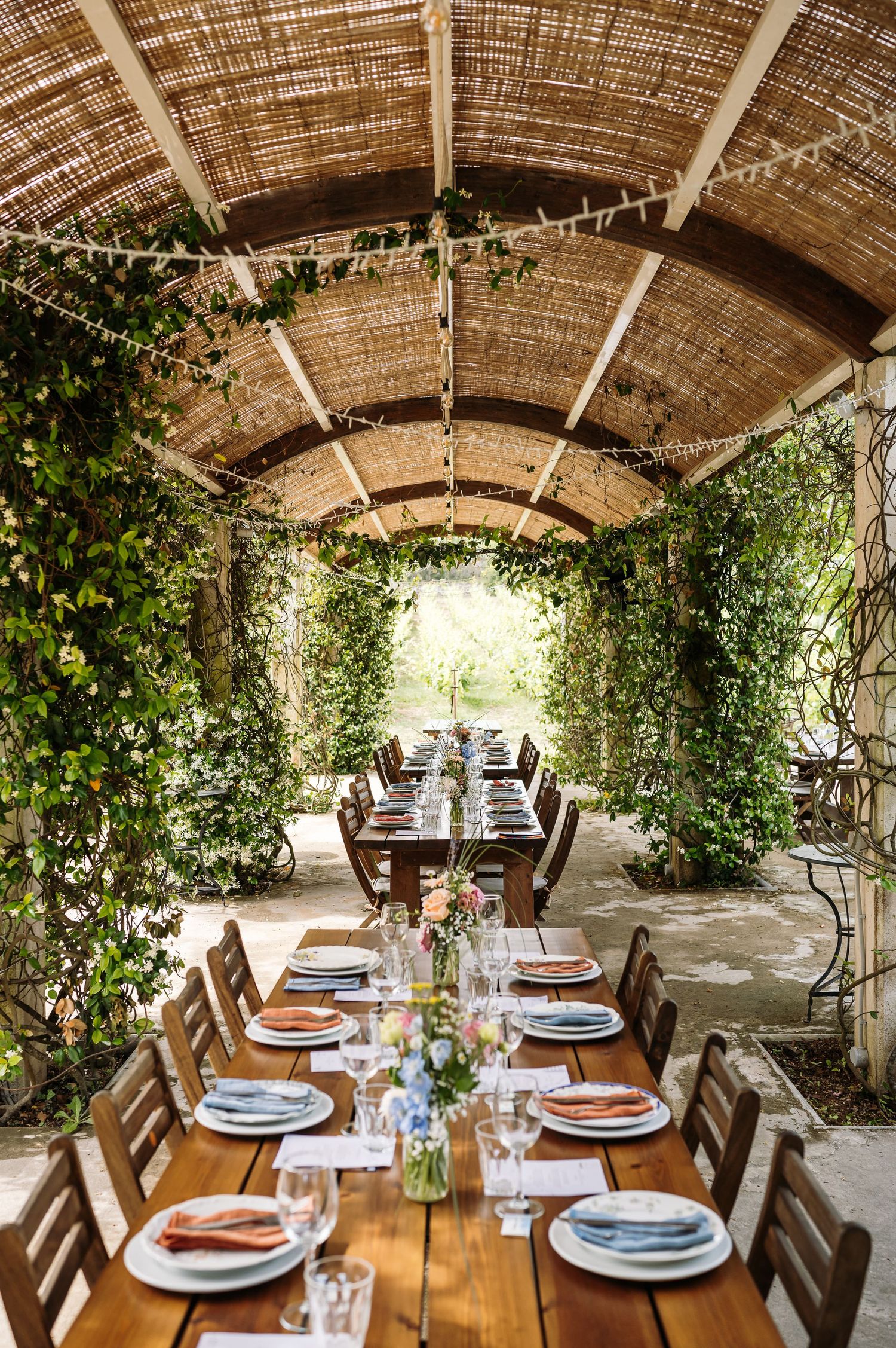 Rustic outdoor dining area with wooden tables set under a covered pergola.