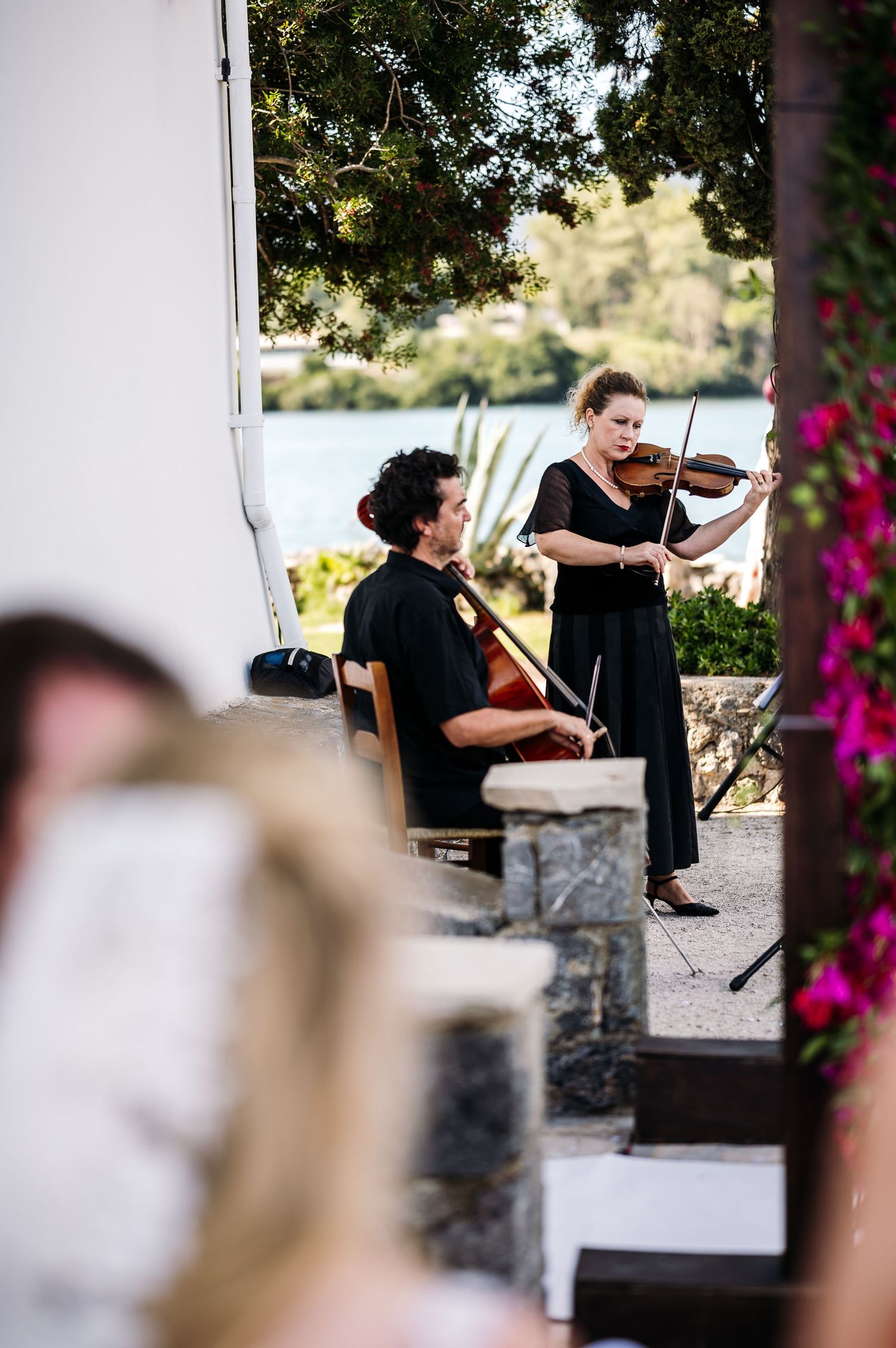 Musicians performing with violins at an outdoor wedding venue.