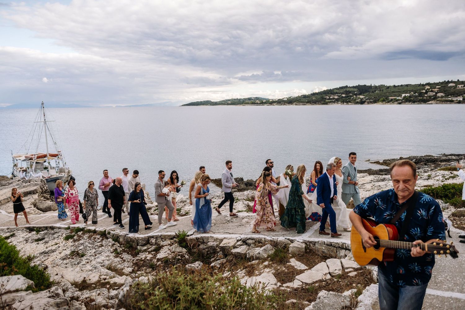 Panoramic view of wedding guests gathered on a rocky coastal overlook.