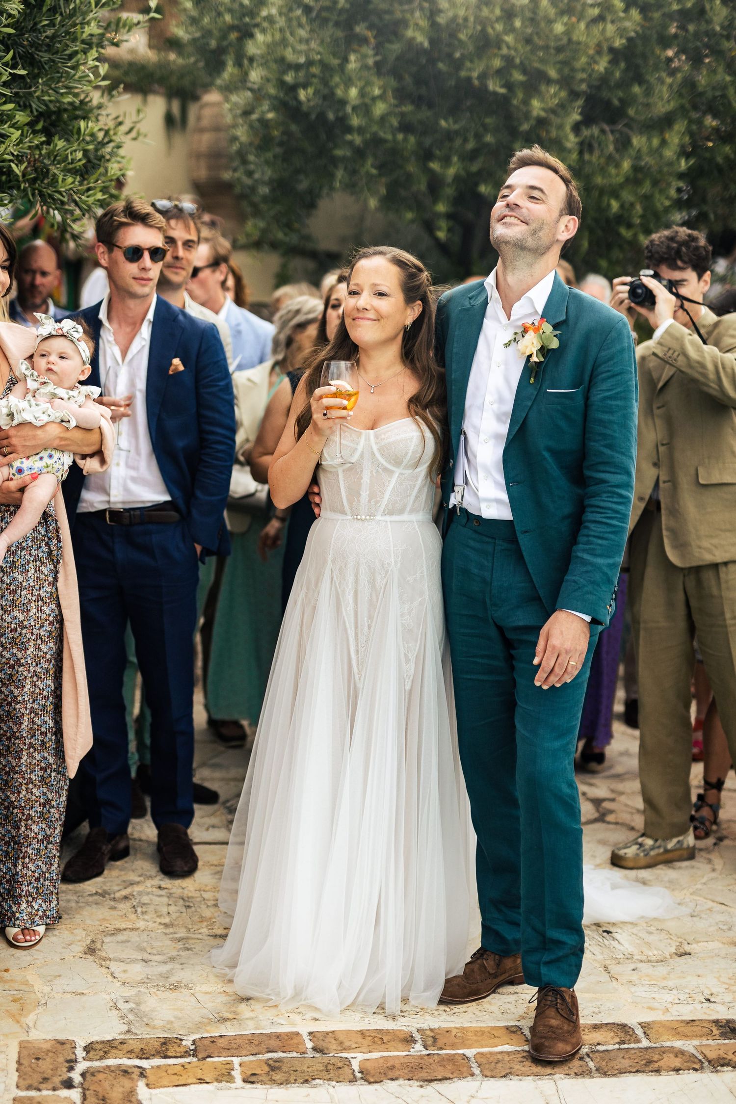 Wedding celebration with guests in formal attire gathered outdoors.