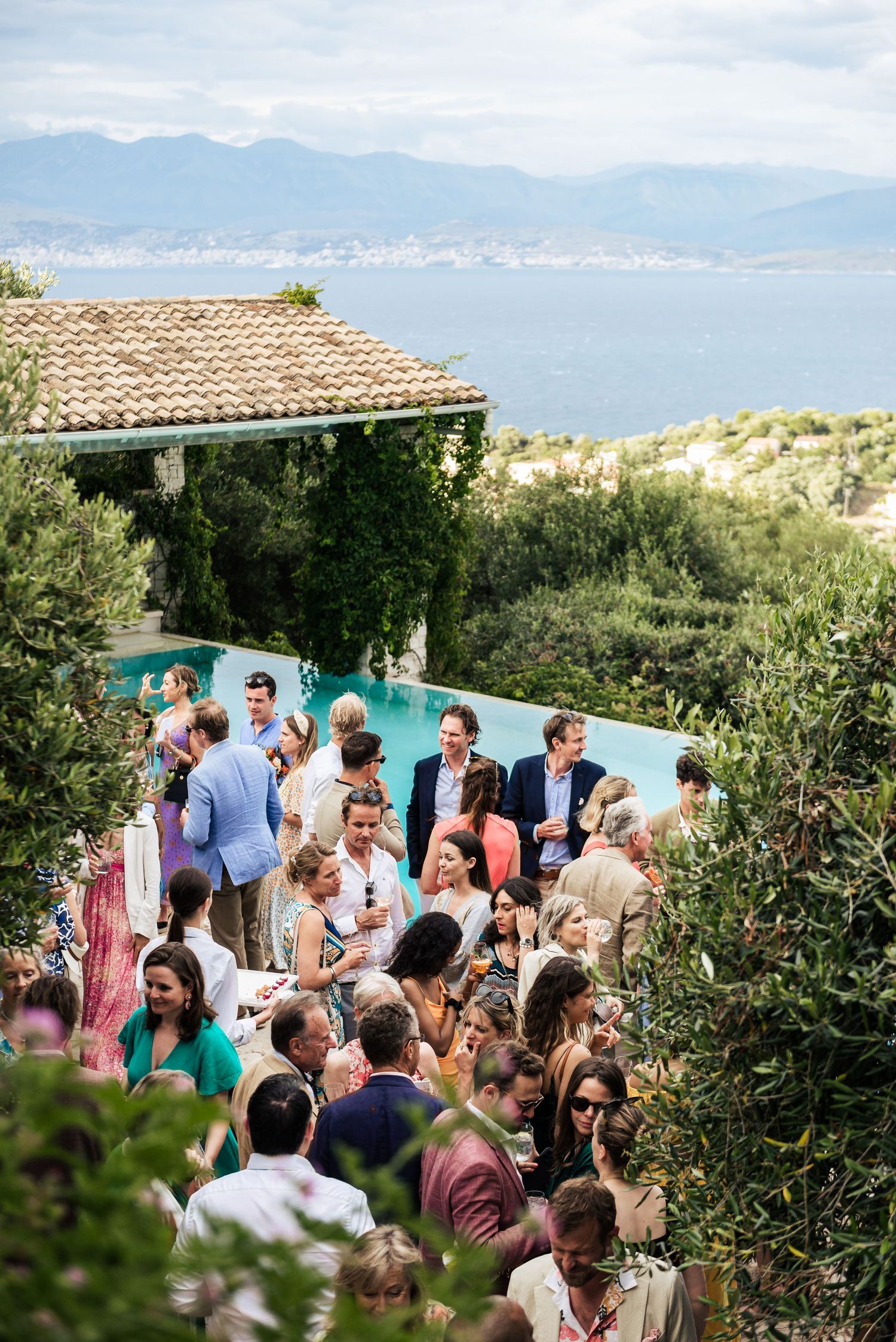 Wedding guests gathered around a pool with stunning coastal mountain views.