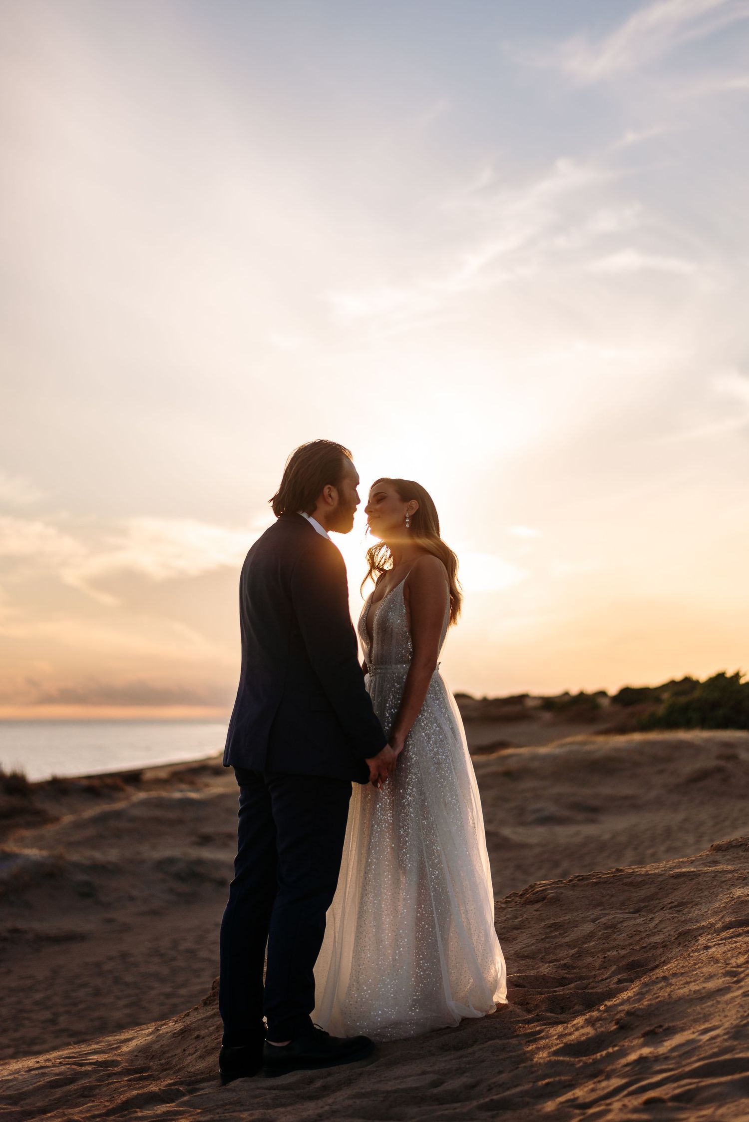 A romantic wedding photoshoot at sunset on a coastal cliff.
