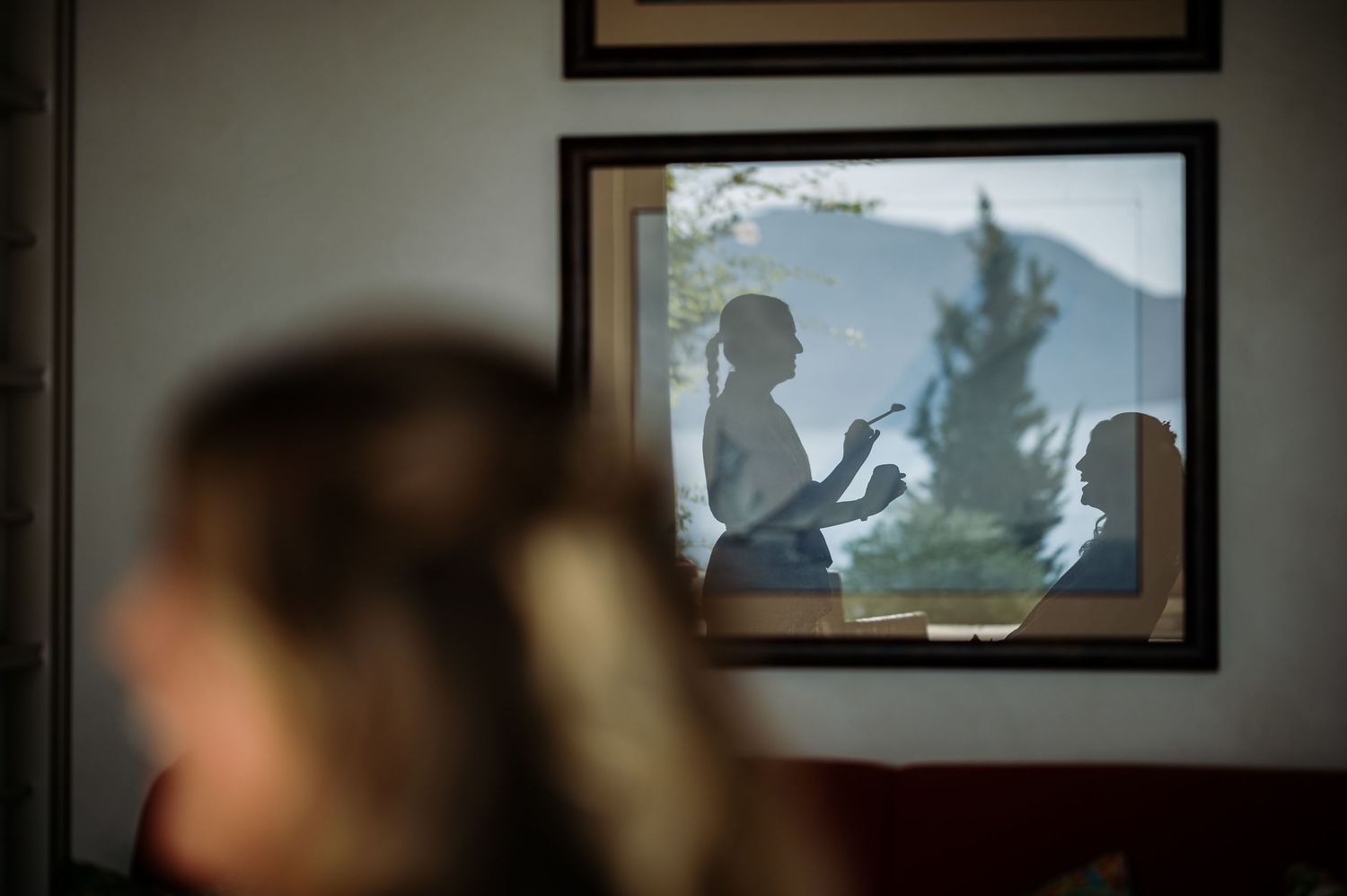 Silhouetted framed artwork hanging on wall with natural light creating shadow effects.