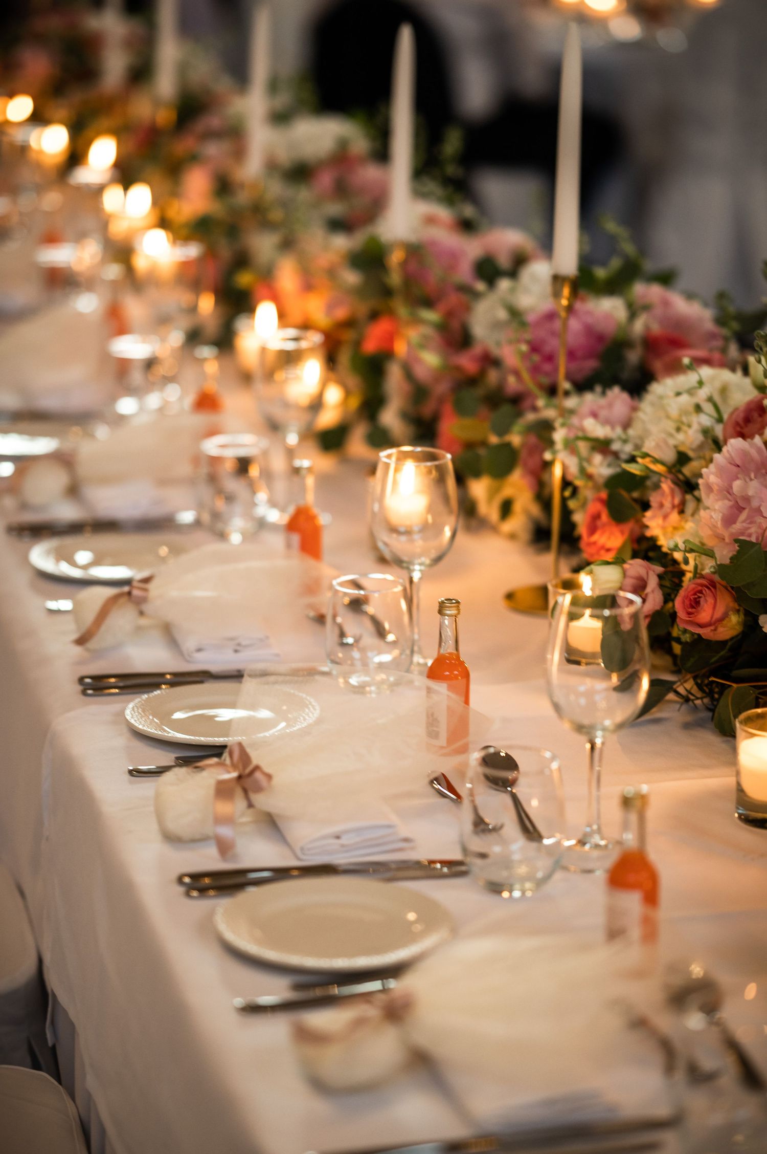 Elegant wedding table setting with candlelight, floral arrangements, and white linens.