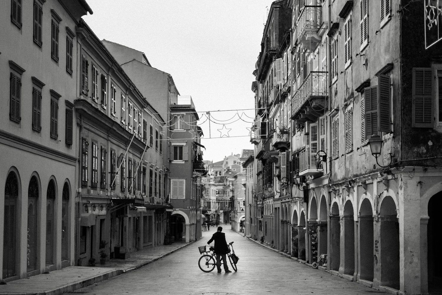 Empty historic street with arched colonnades and a lone bicycle in the distance.