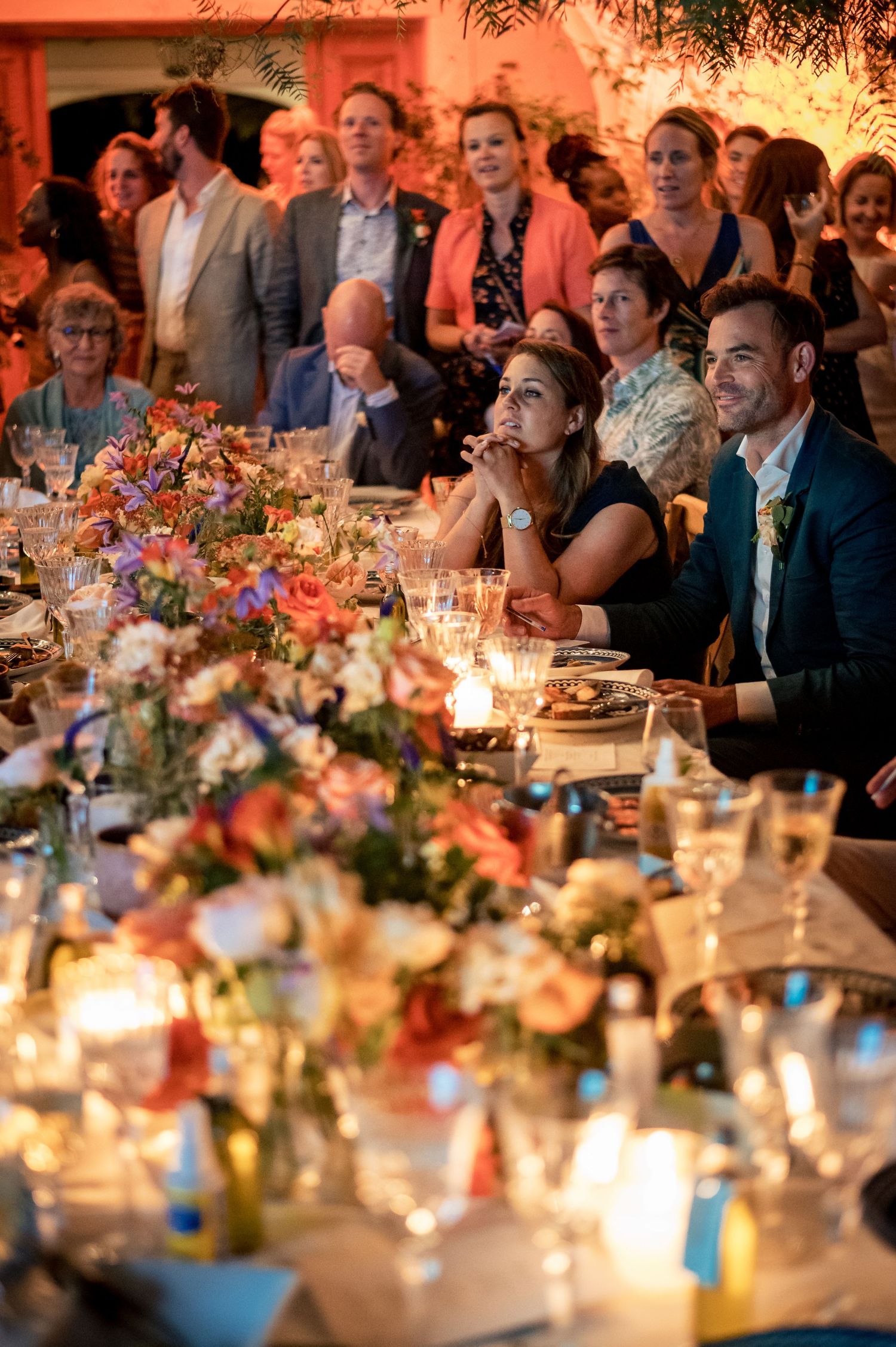 Elegant wedding reception table with colorful floral arrangements and glowing candlelight.