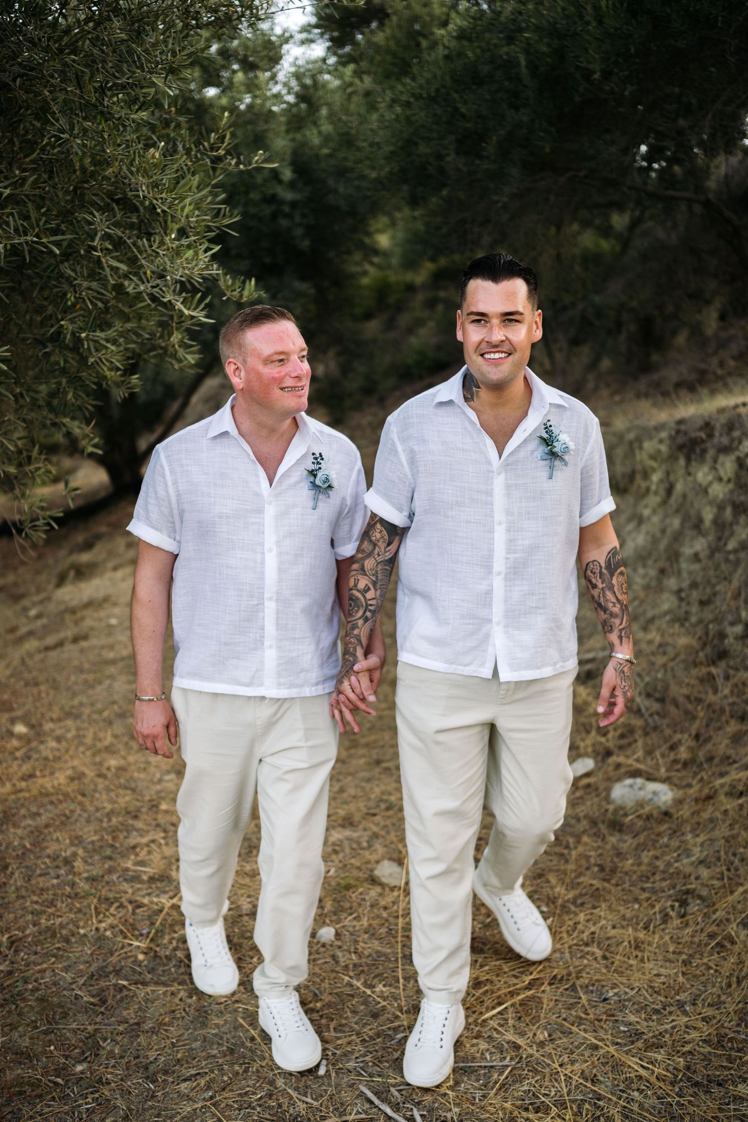 Couple in crisp white shirts and khaki pants walking together on nature trail.