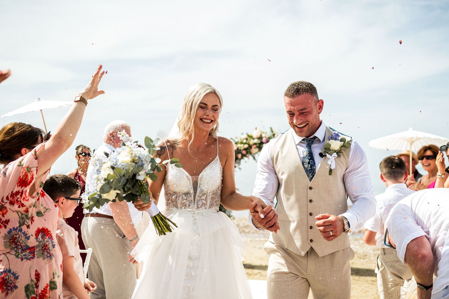 Joyful celebration moment during a beach wedding with guests cheering in the background.