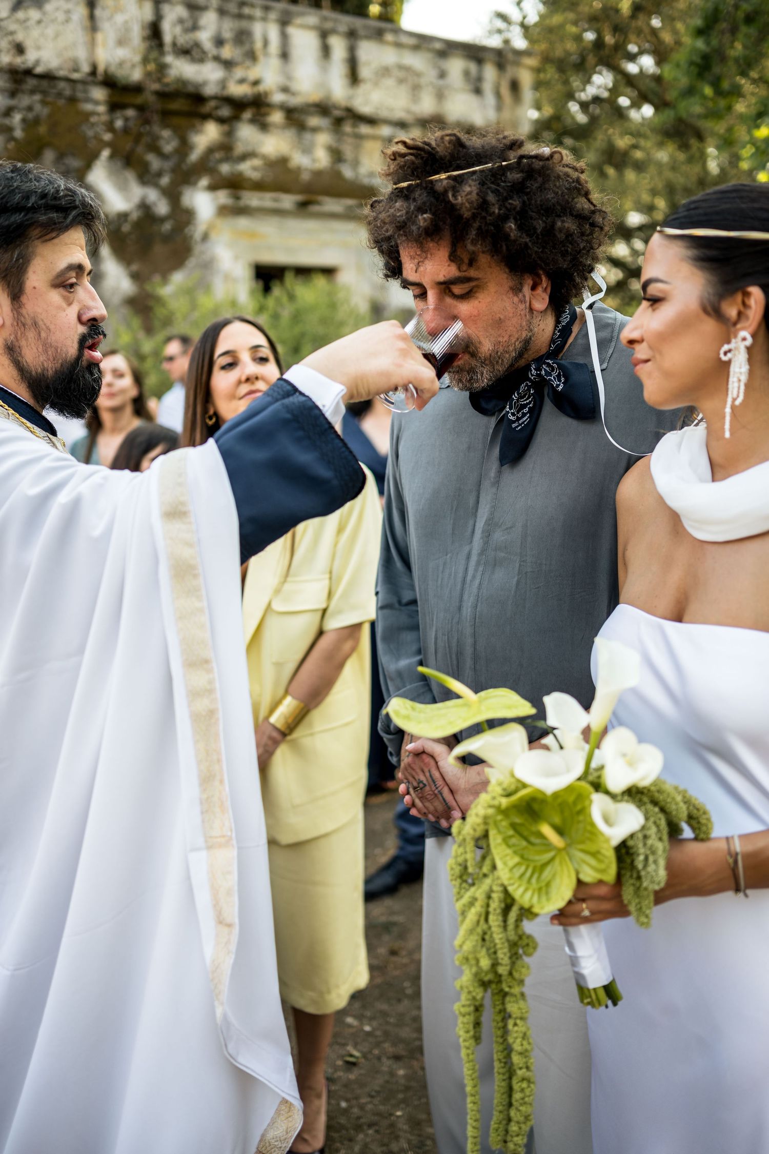 Wedding guests in white and yellow attire mingle during an elegant outdoor gathering.