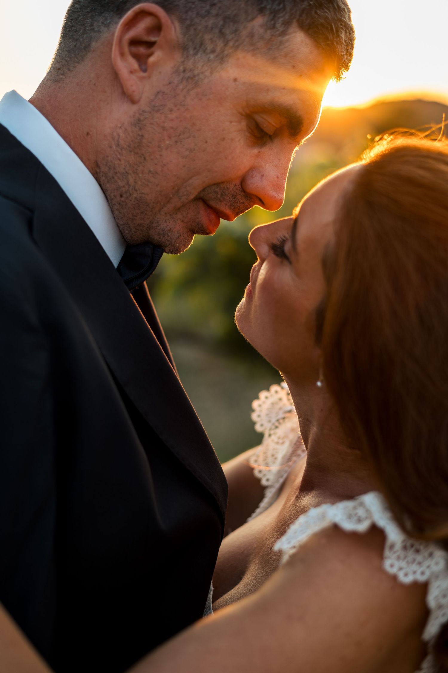 Intimate close-up of newlyweds sharing a tender moment at sunset.