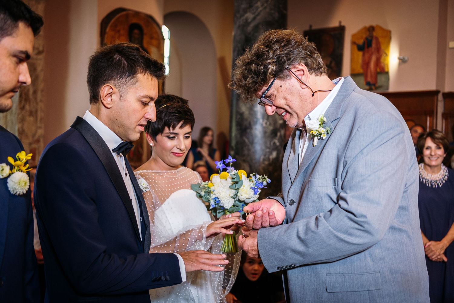 Wedding celebration inside warm-toned room with arched doorways and floral decorations.