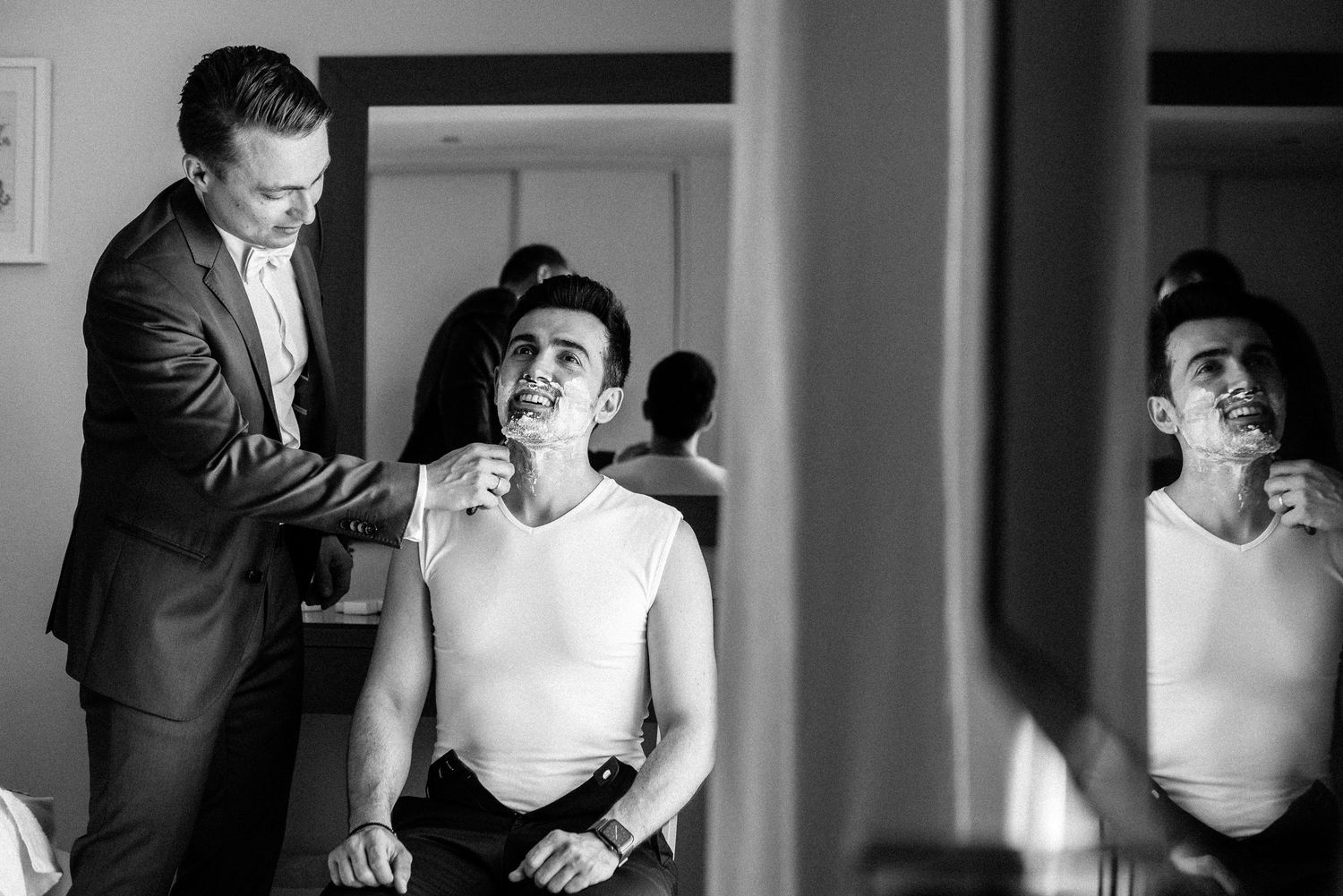Black and white photo sequence showing groom getting ready and adjusting formal attire.