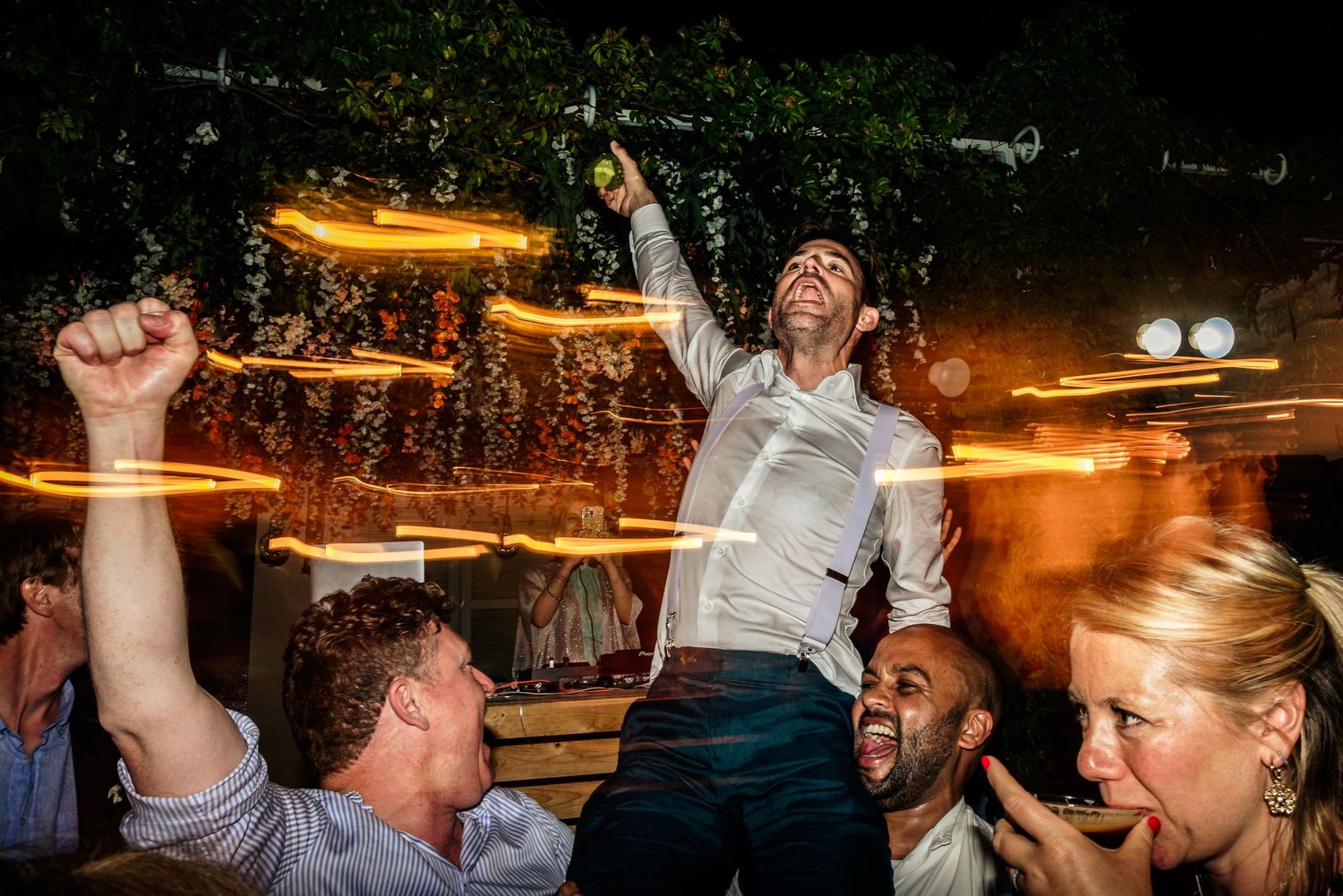 Party crowd dancing and celebrating under warm ambient lighting.