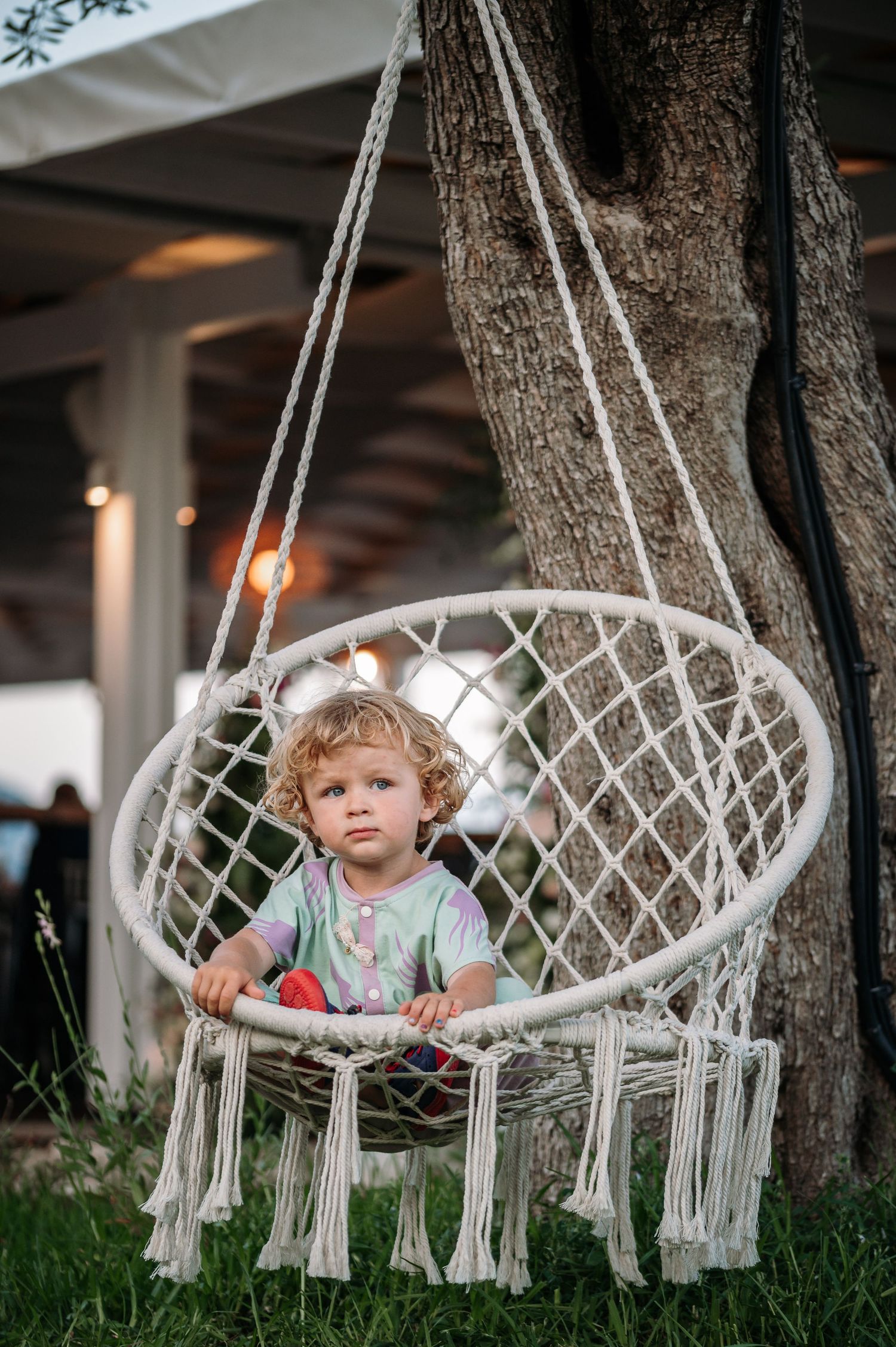 Macrame hanging chair swing decorated with tassels between trees.